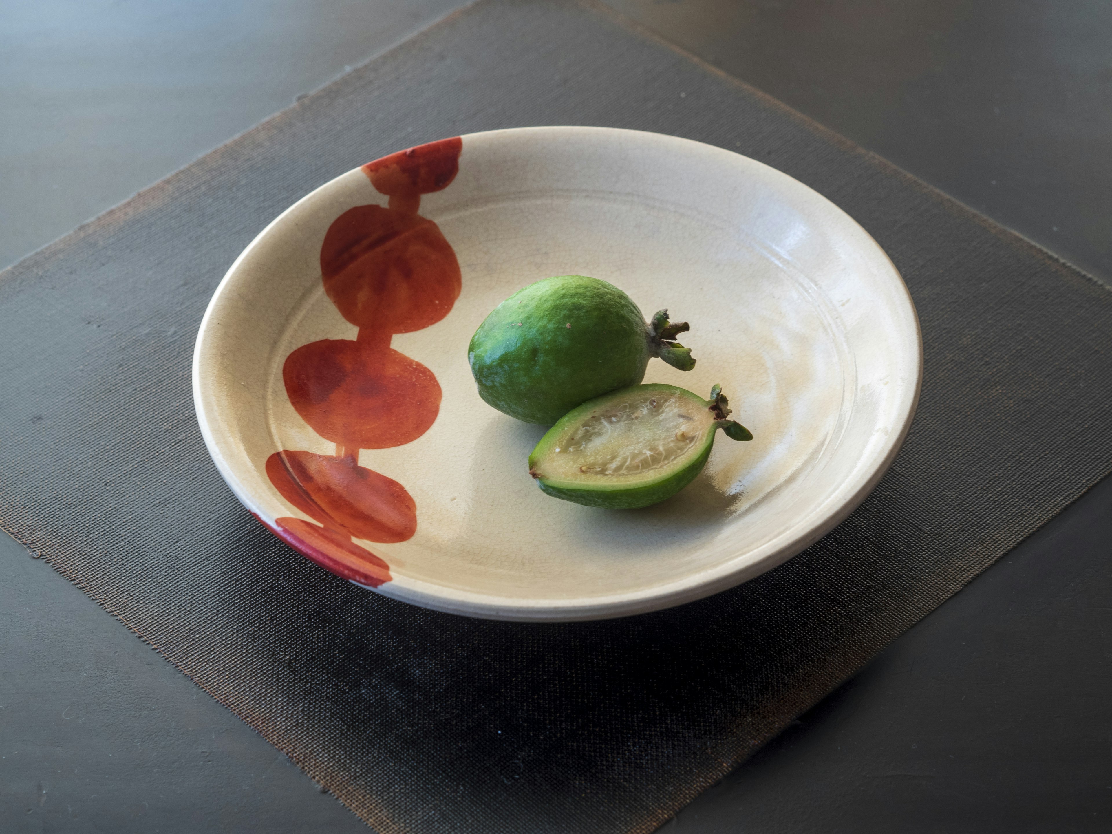 Une assiette blanche avec un fruit vert et un fruit tranché dessus