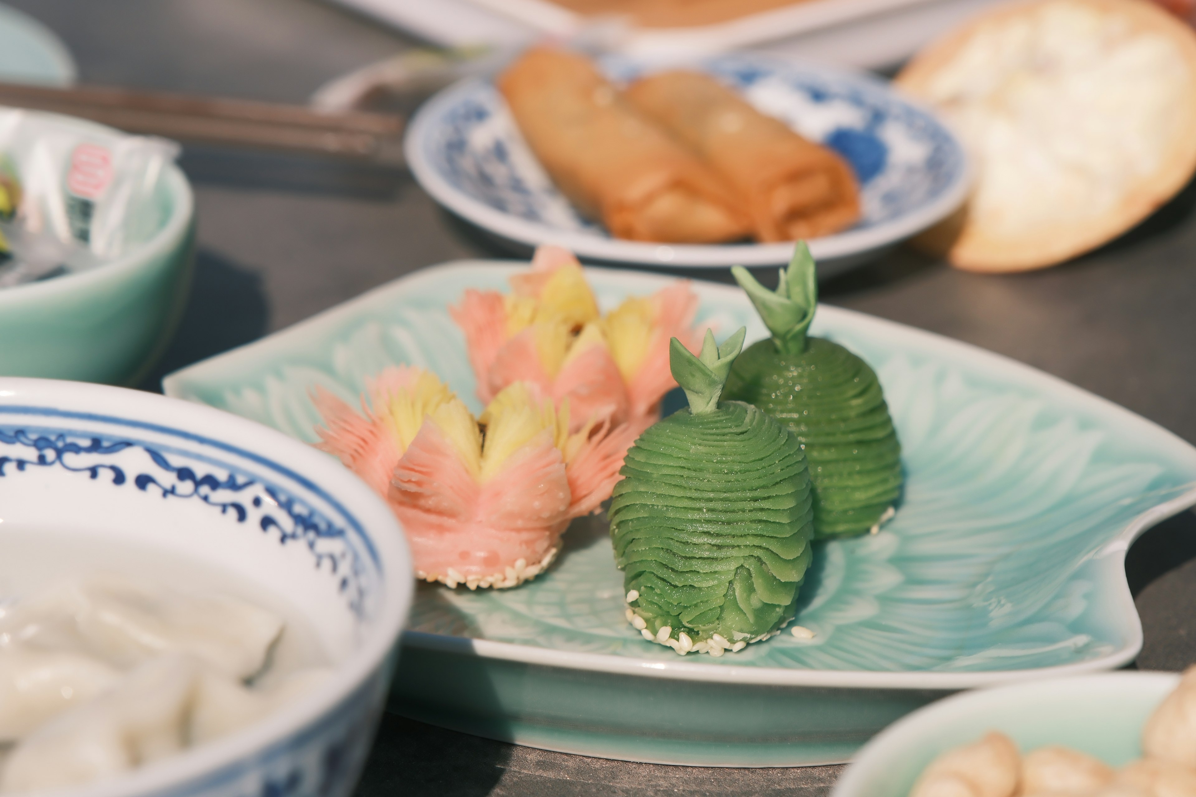 Colorful wagashi displayed on a decorative plate with surrounding dishes