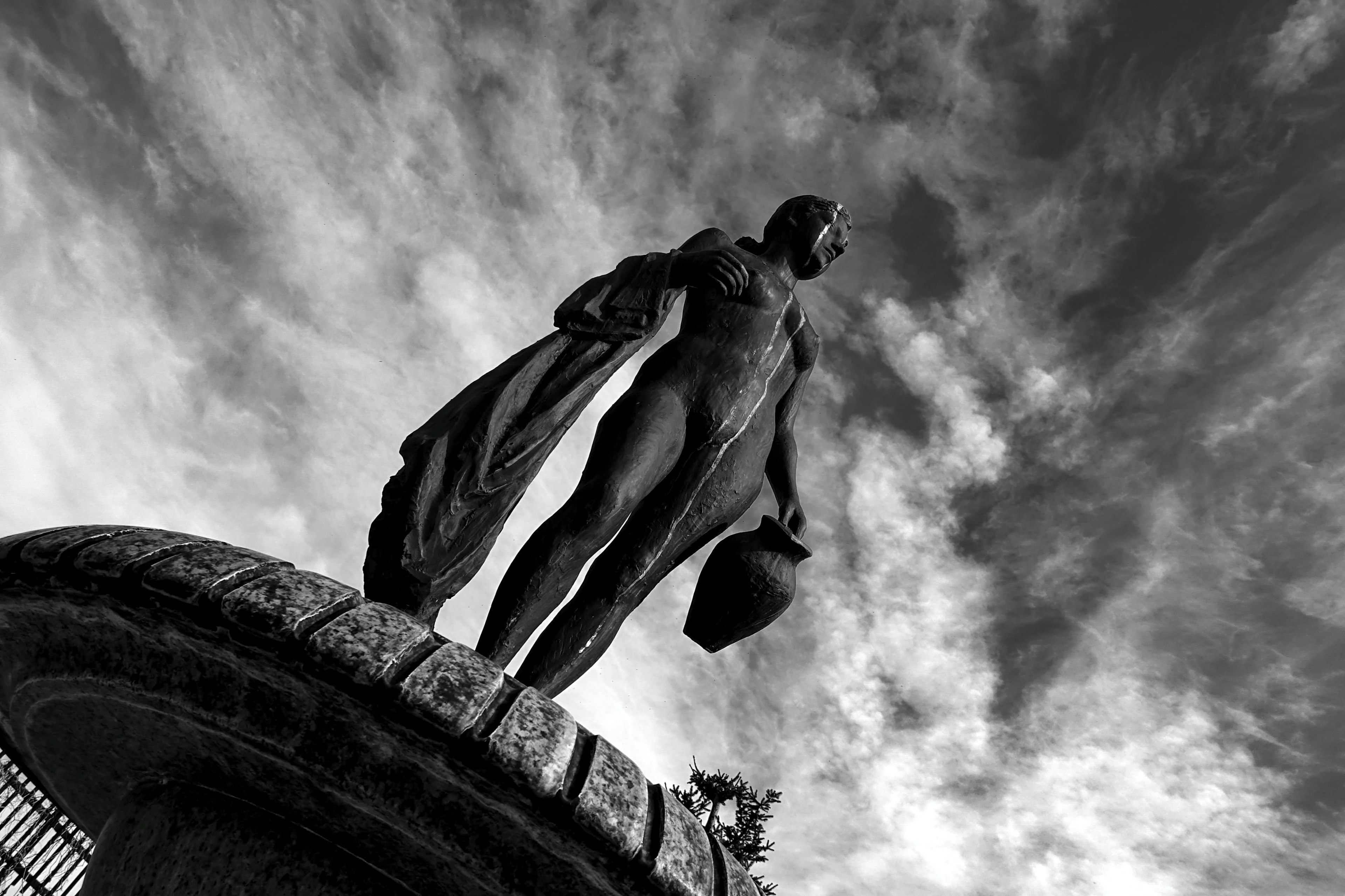 Une statue se tenant devant un ciel noir et blanc