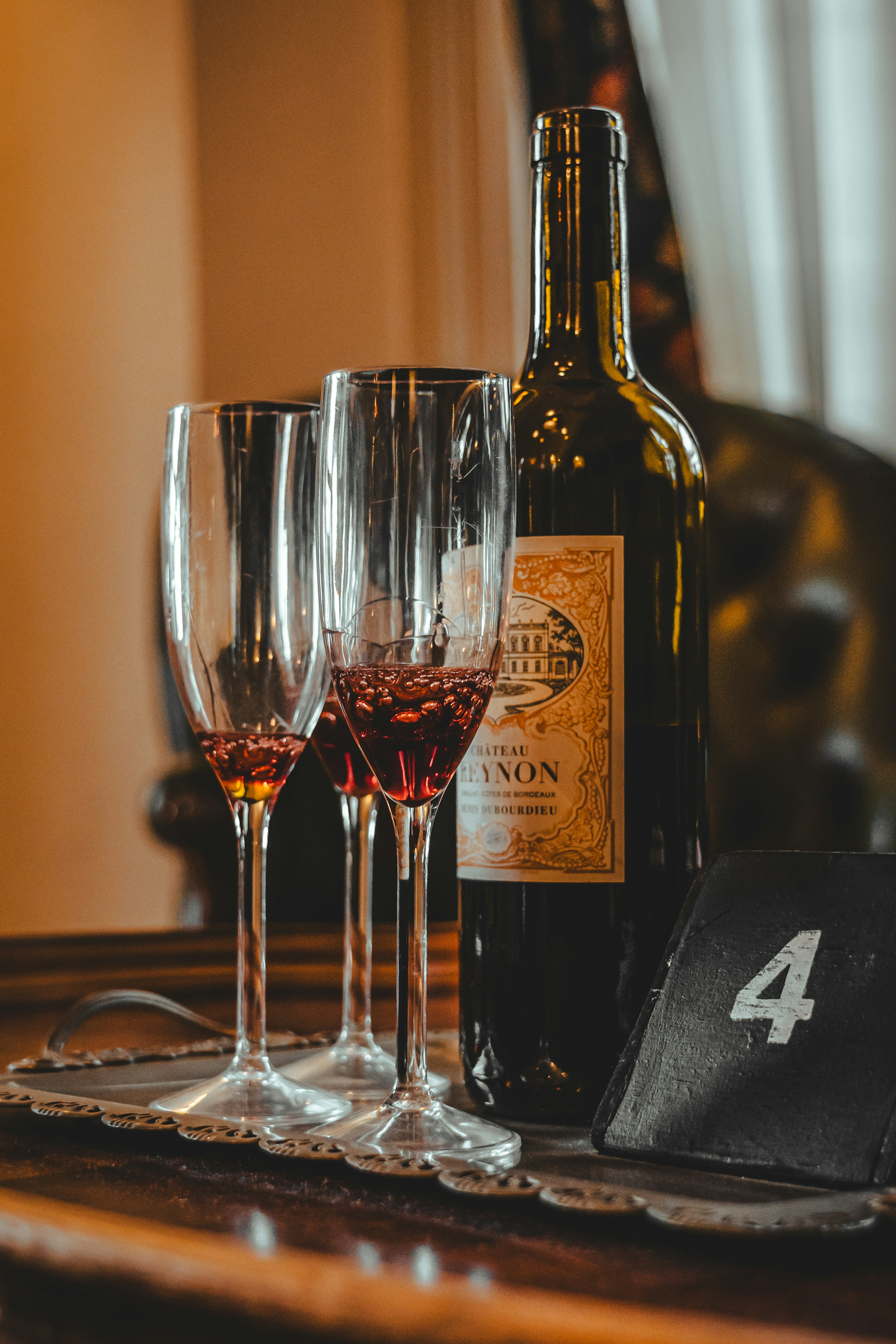 Una botella de vino tinto y tres copas están sobre una mesa