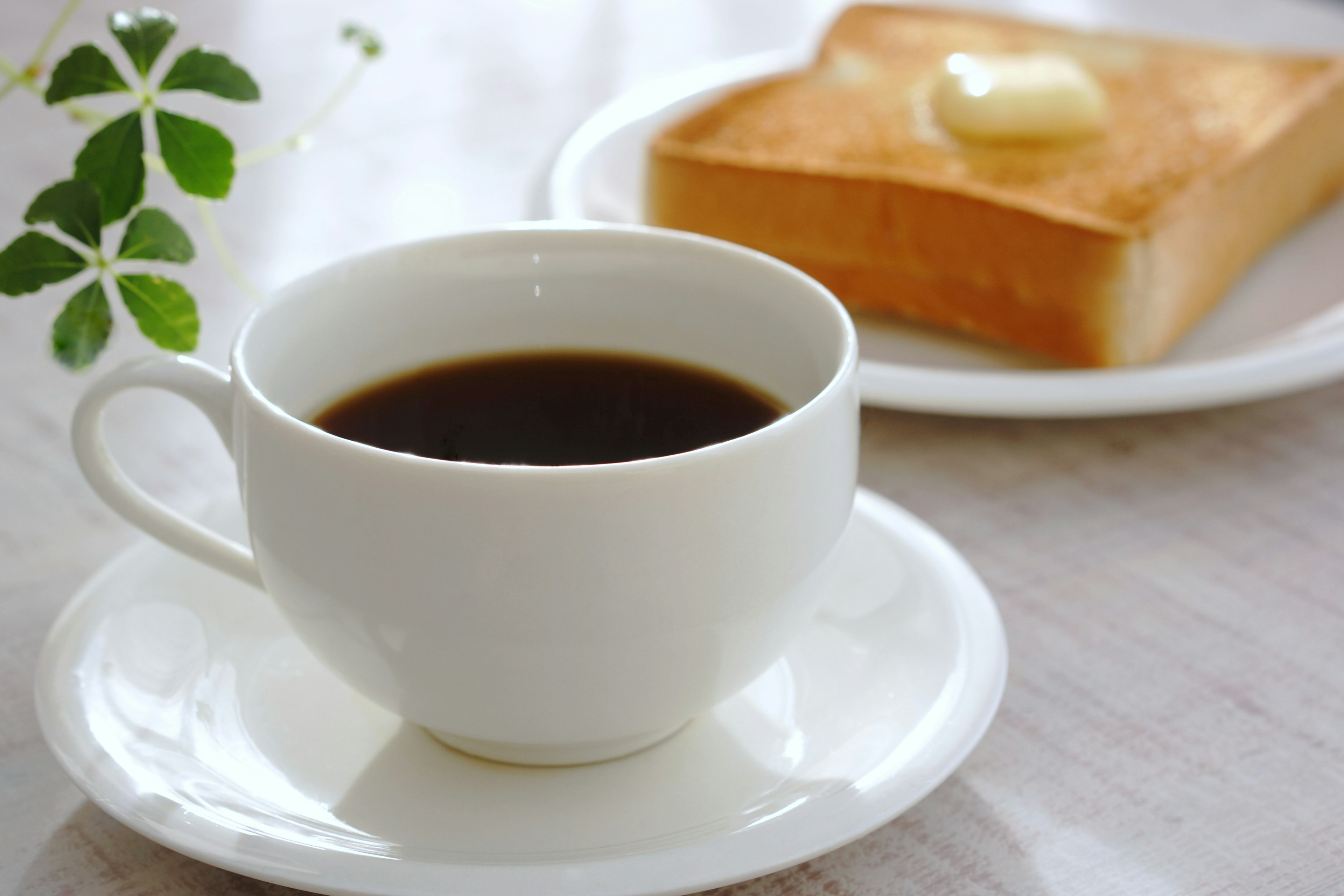 Sebuah cangkir kopi hitam dengan sepotong roti bakar dengan mentega