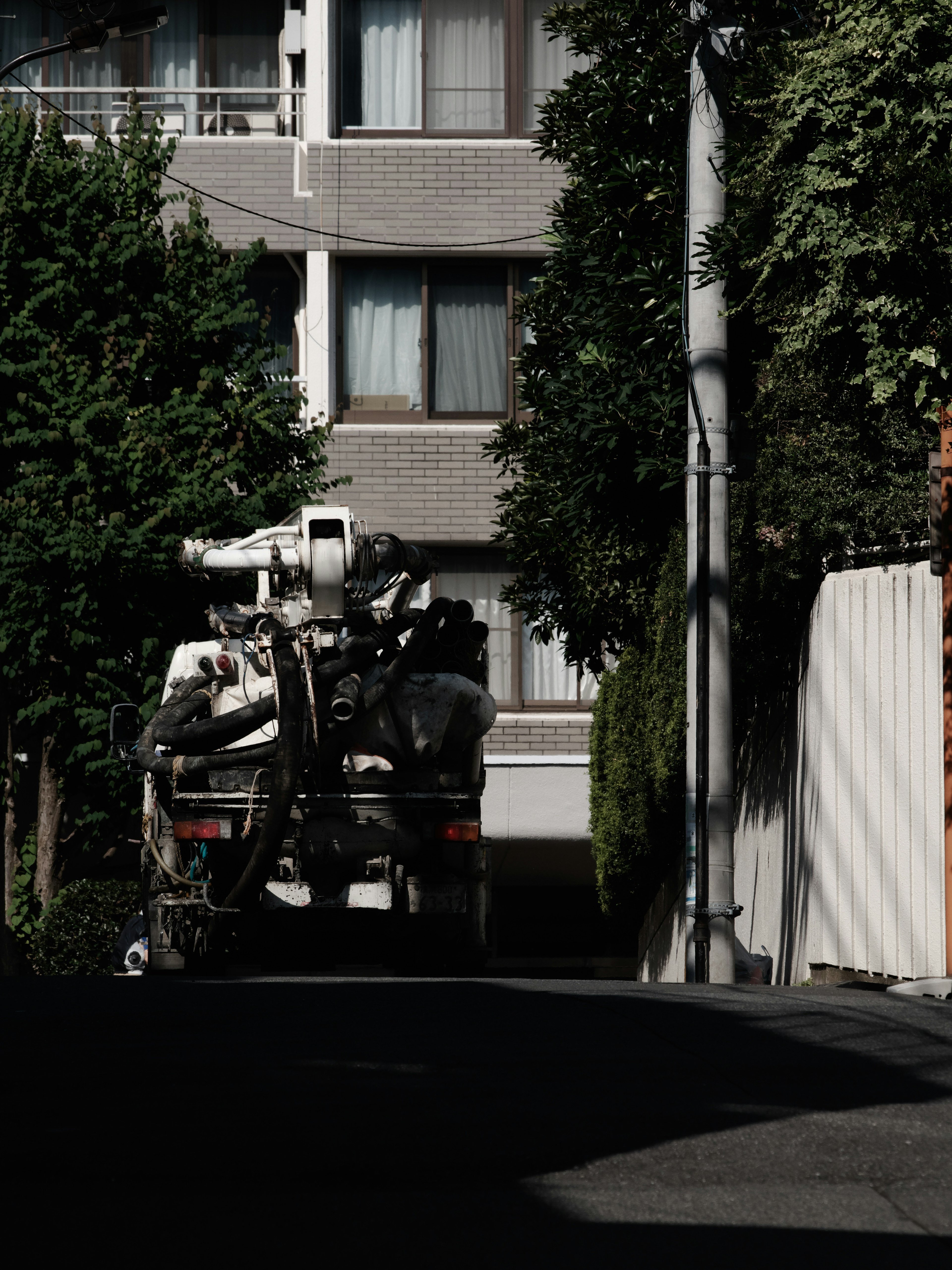 暗い路地に停まった大型トラックと周囲の緑