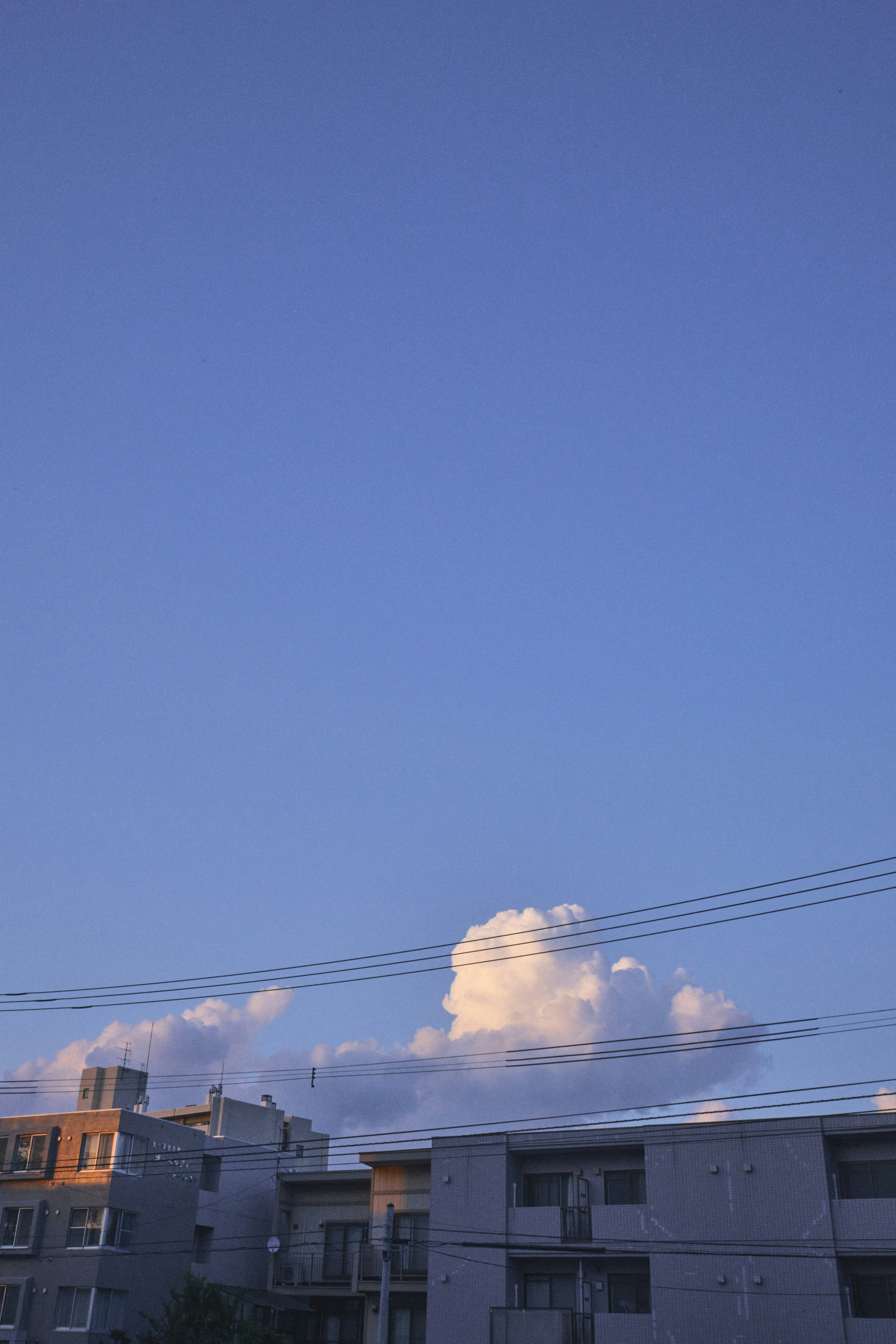 Clear blue sky with fluffy white clouds over urban buildings