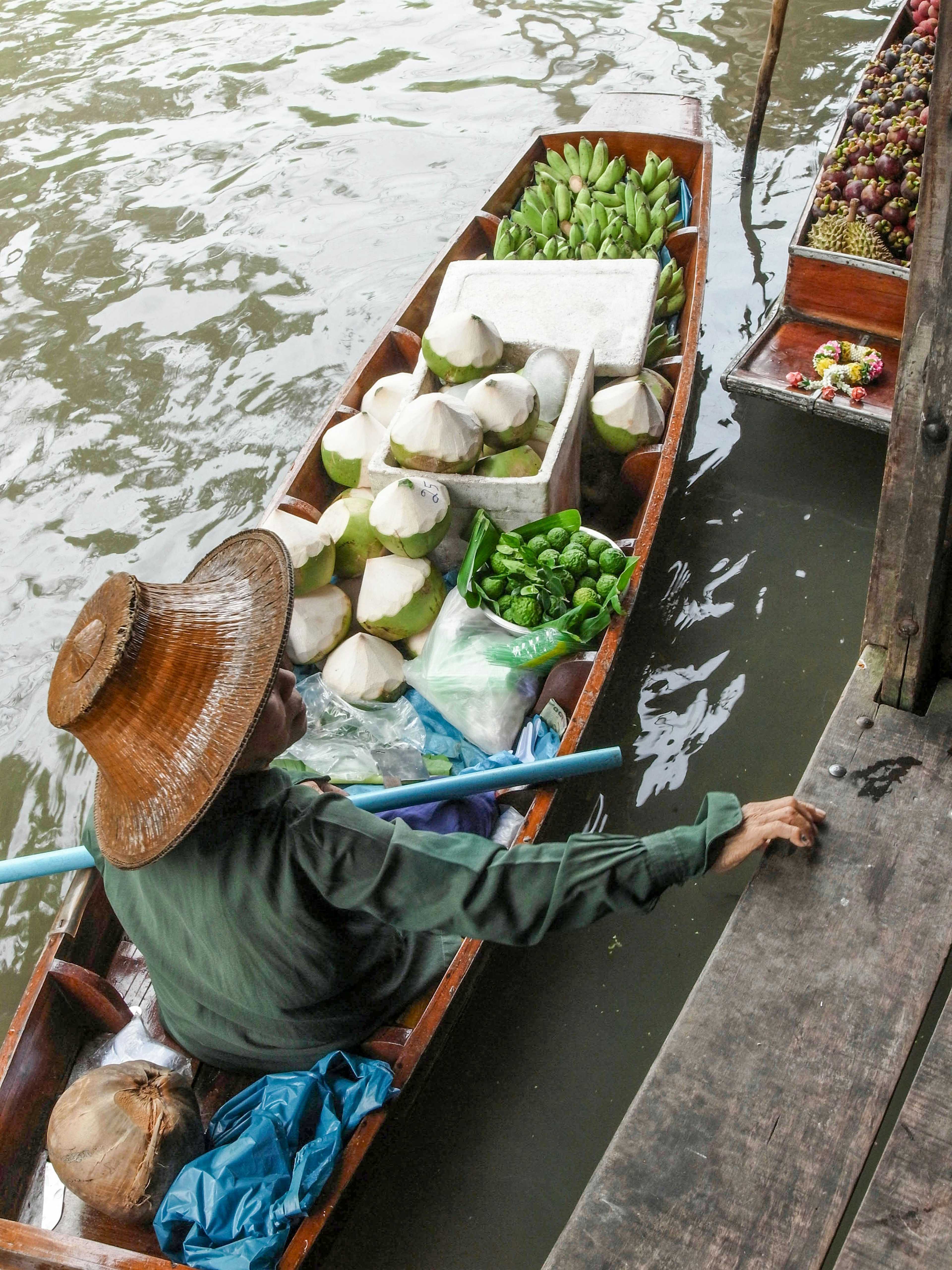 Ein Verkäufer in einem Boot, der frische Produkte entlang eines Gewässers transportiert