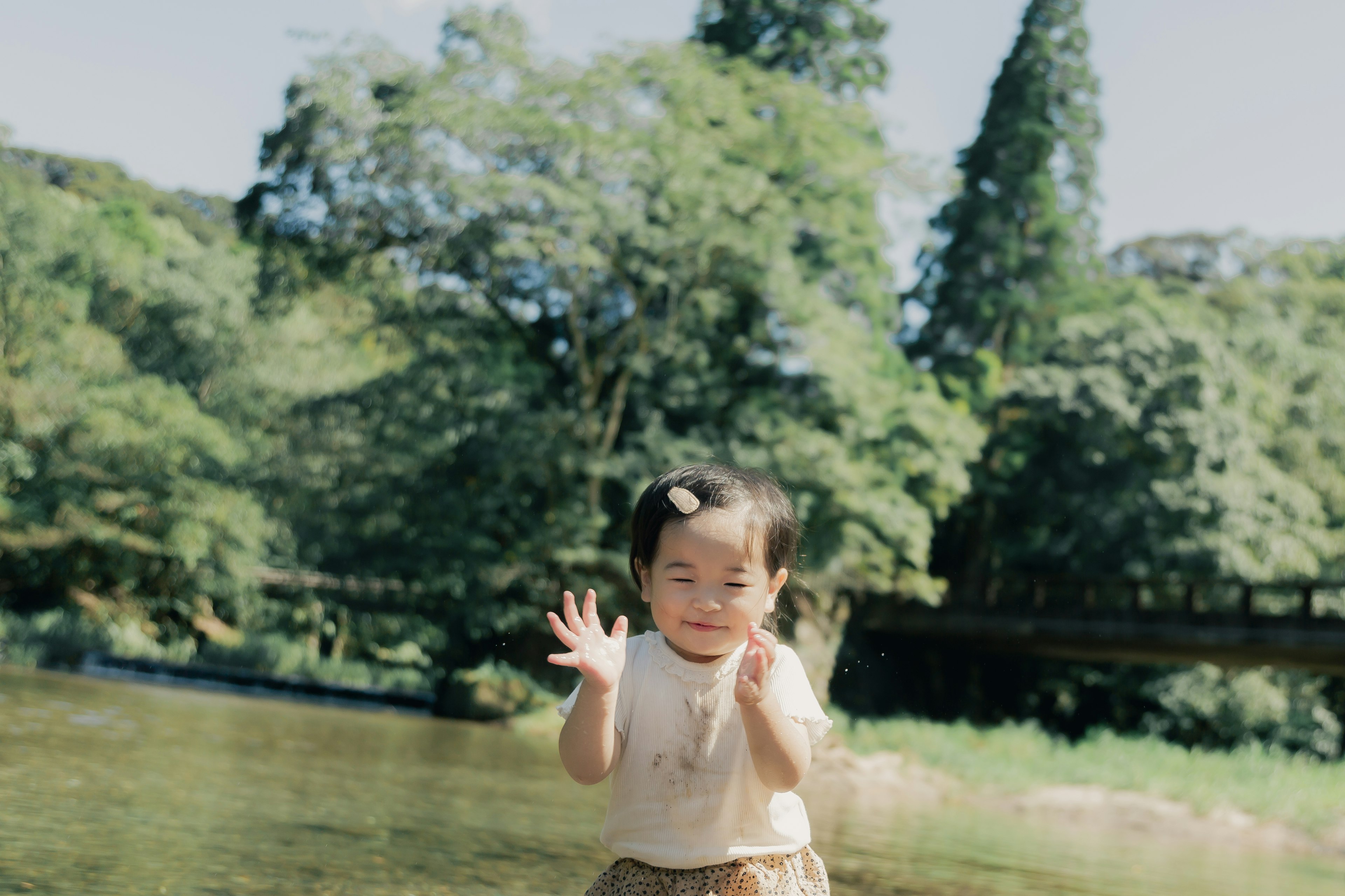 小さな女の子が川の近くで遊んでいる様子緑に囲まれた自然の中で