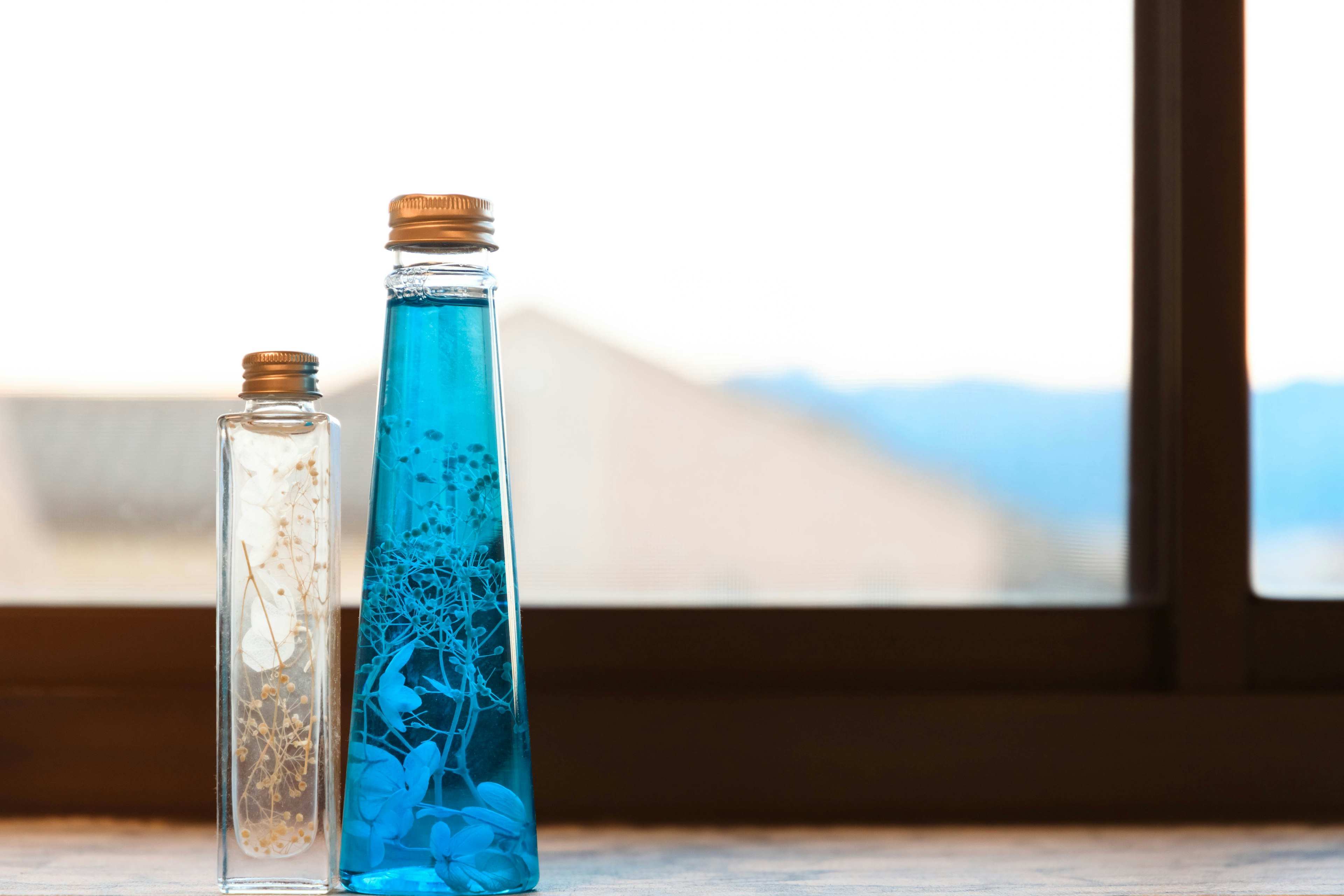 A blue bottle and a clear bottle placed on a windowsill