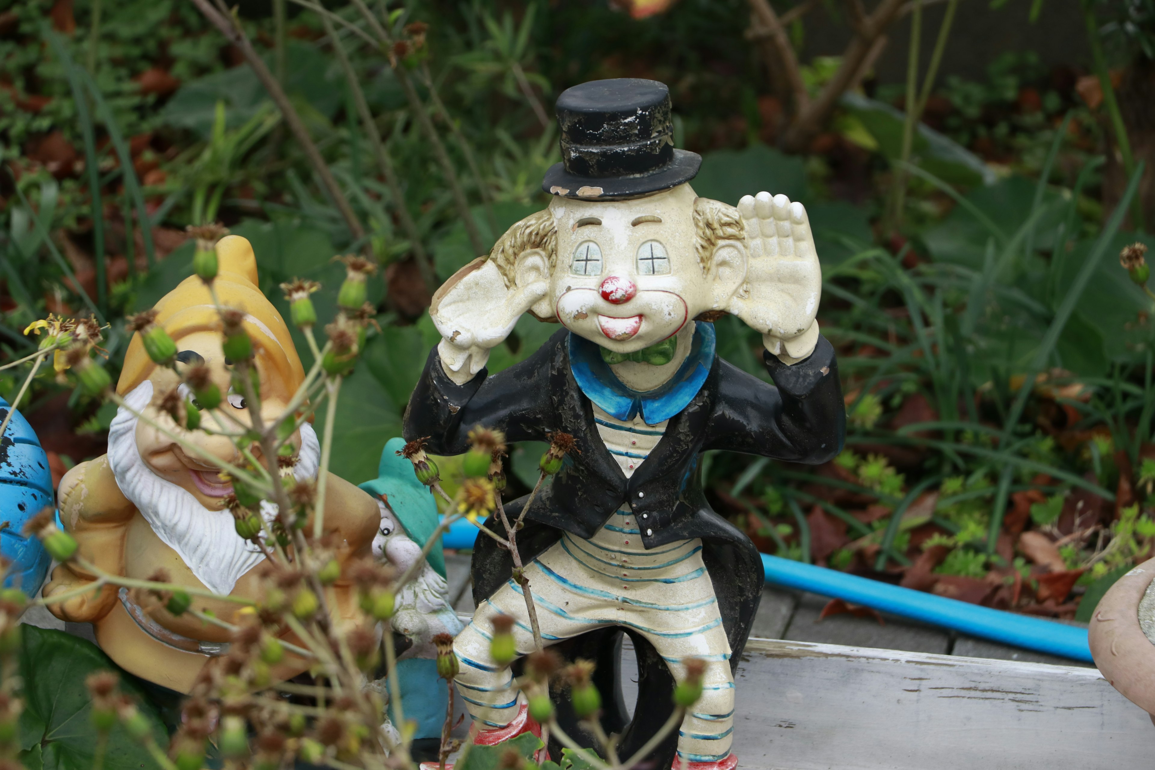 Statua di clown in ceramica colorata in un giardino che ascolta con orecchie esagerate