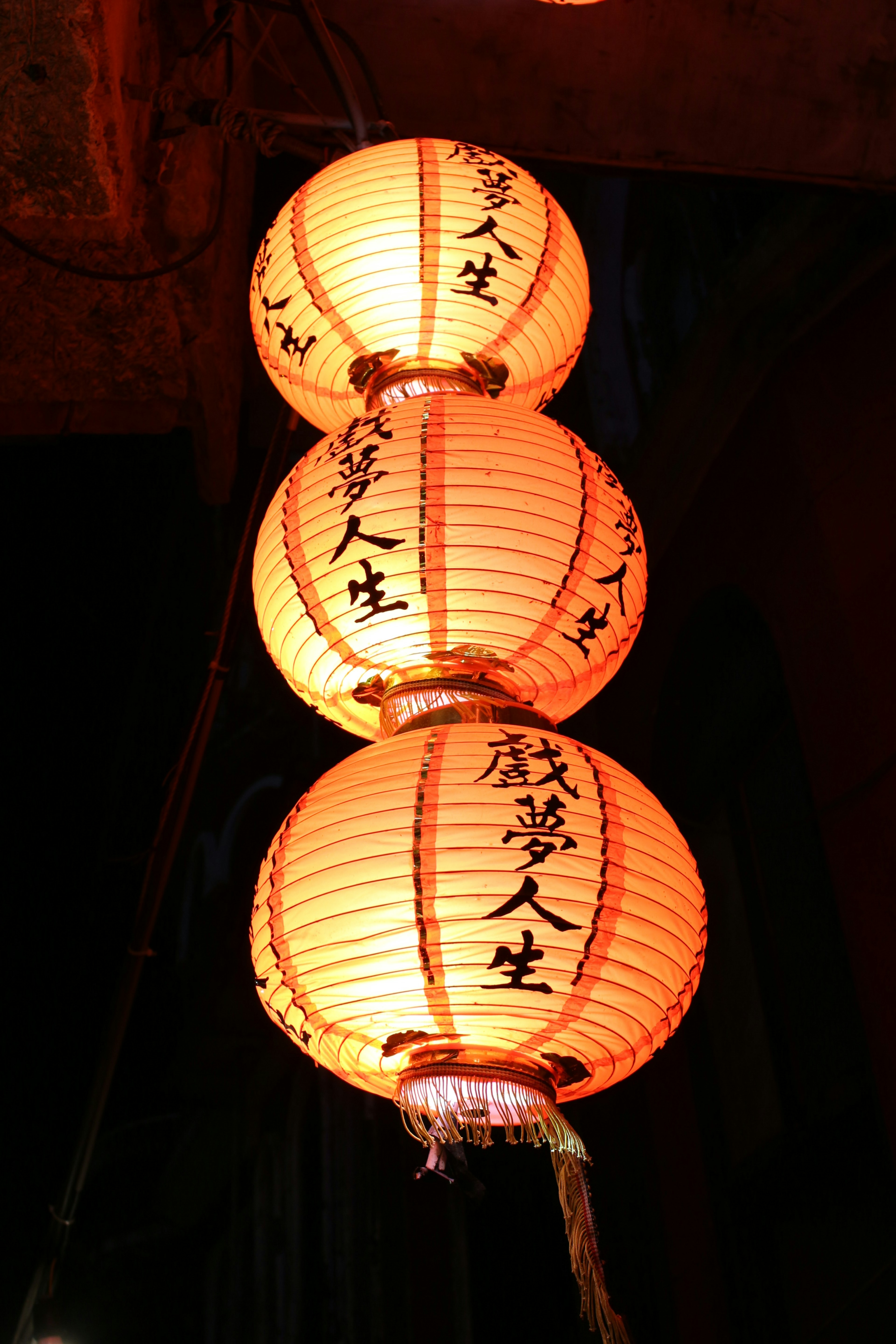 Three orange lanterns hanging with Chinese characters