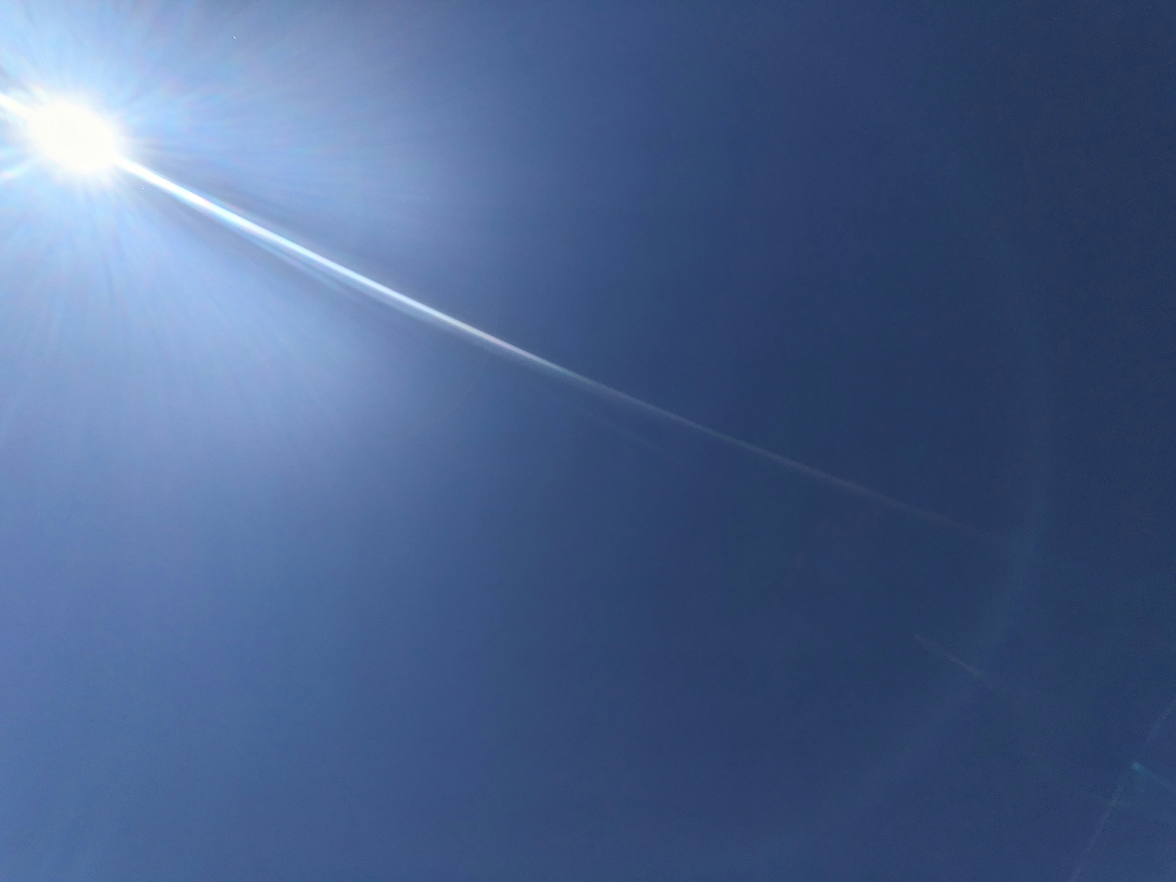 Cielo azul brillante con sol y estela de nubes