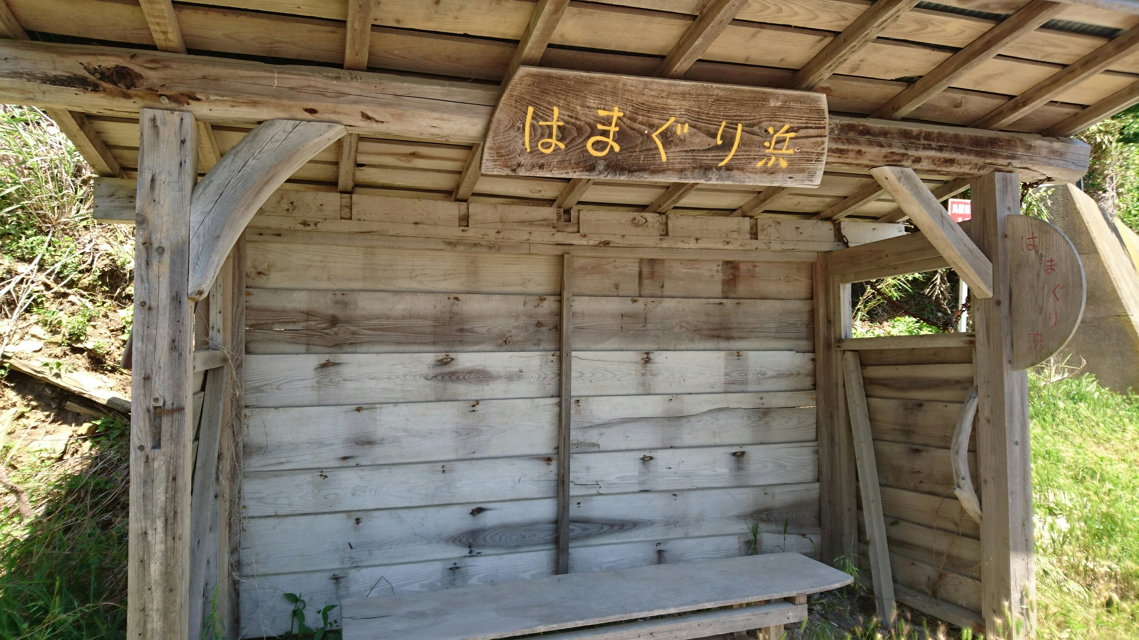 木製のバス停のベンチと屋根がある風景