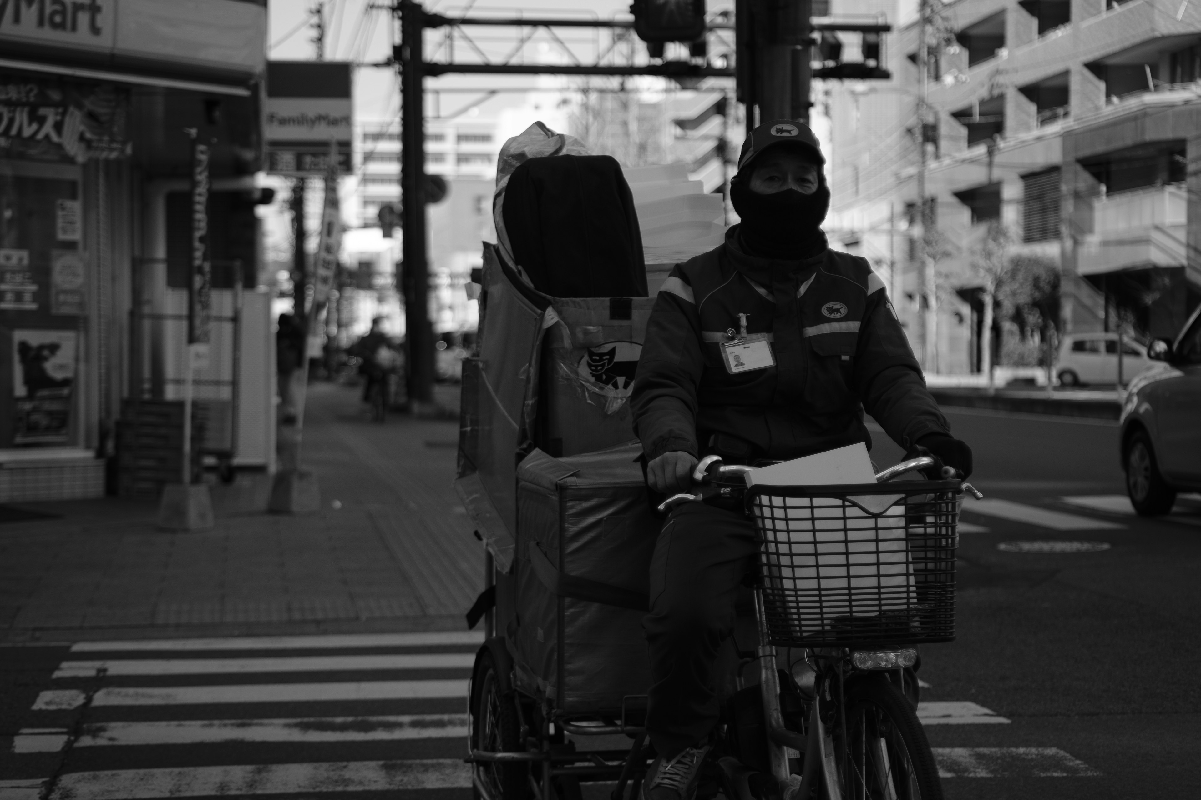 Schwarzweißfoto eines Lieferanten auf einem Fahrrad, der die Straße überquert