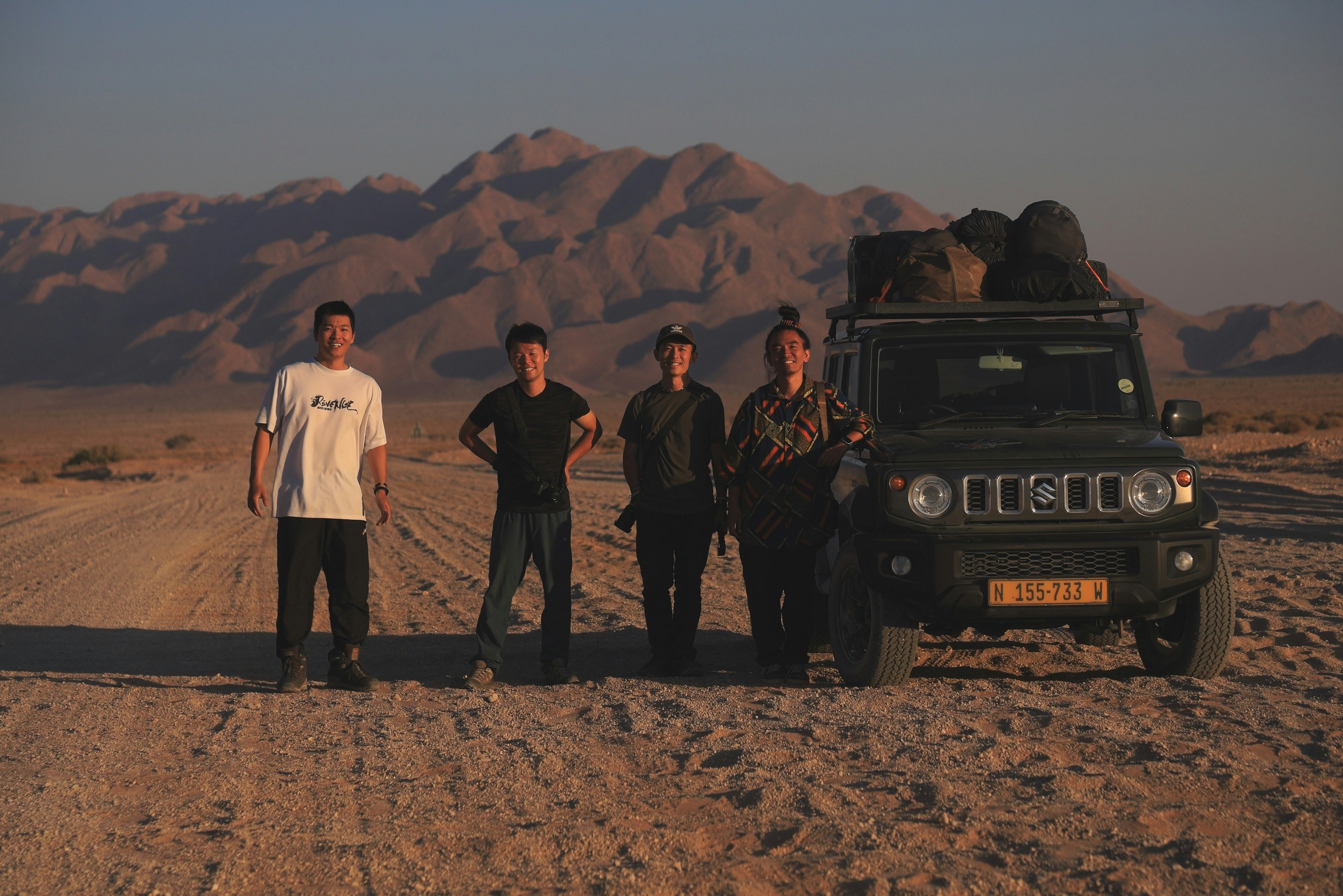 Cinque uomini in piedi in un deserto con un jeep