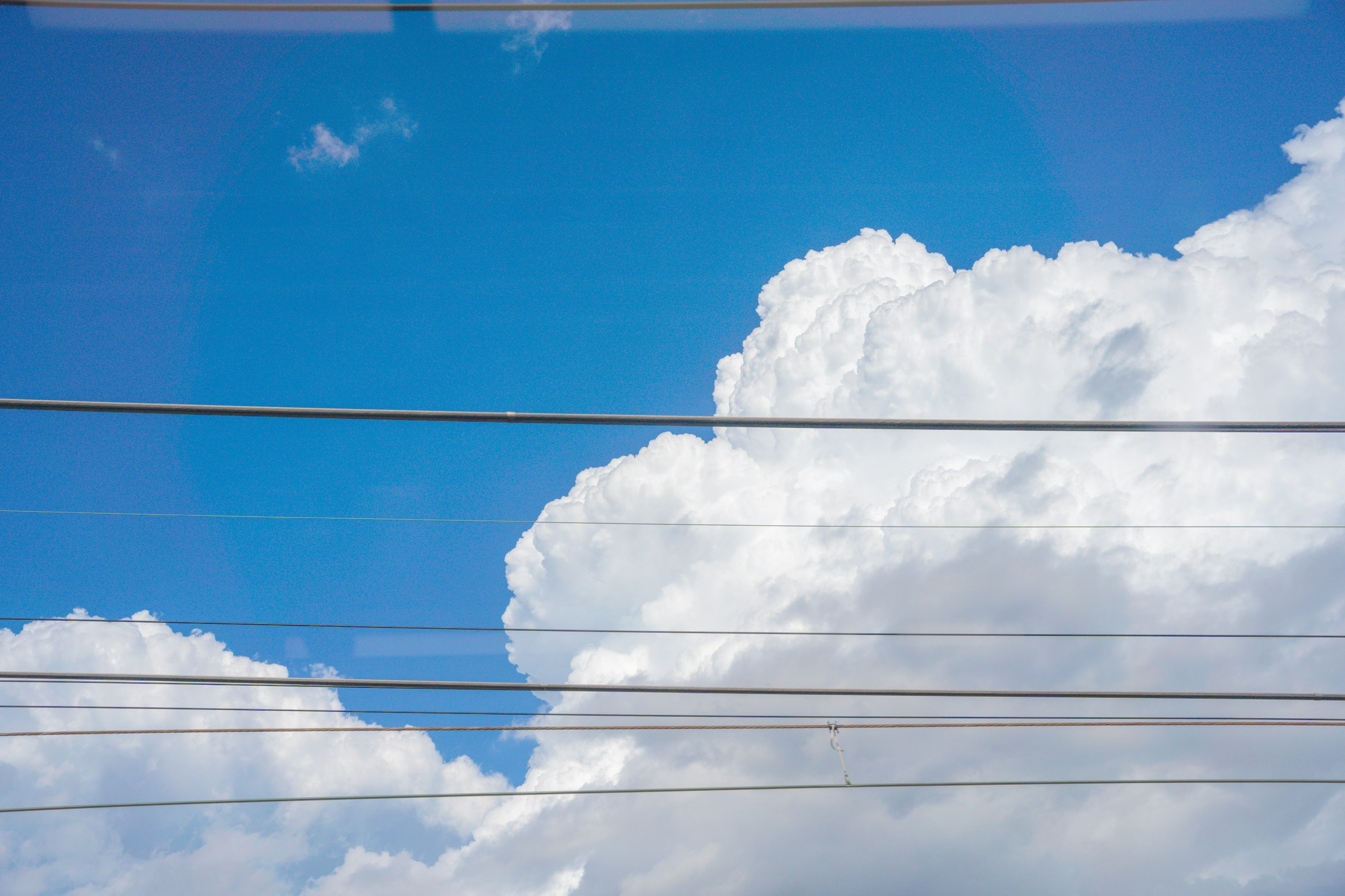 青空と白い雲、電線が横切る風景