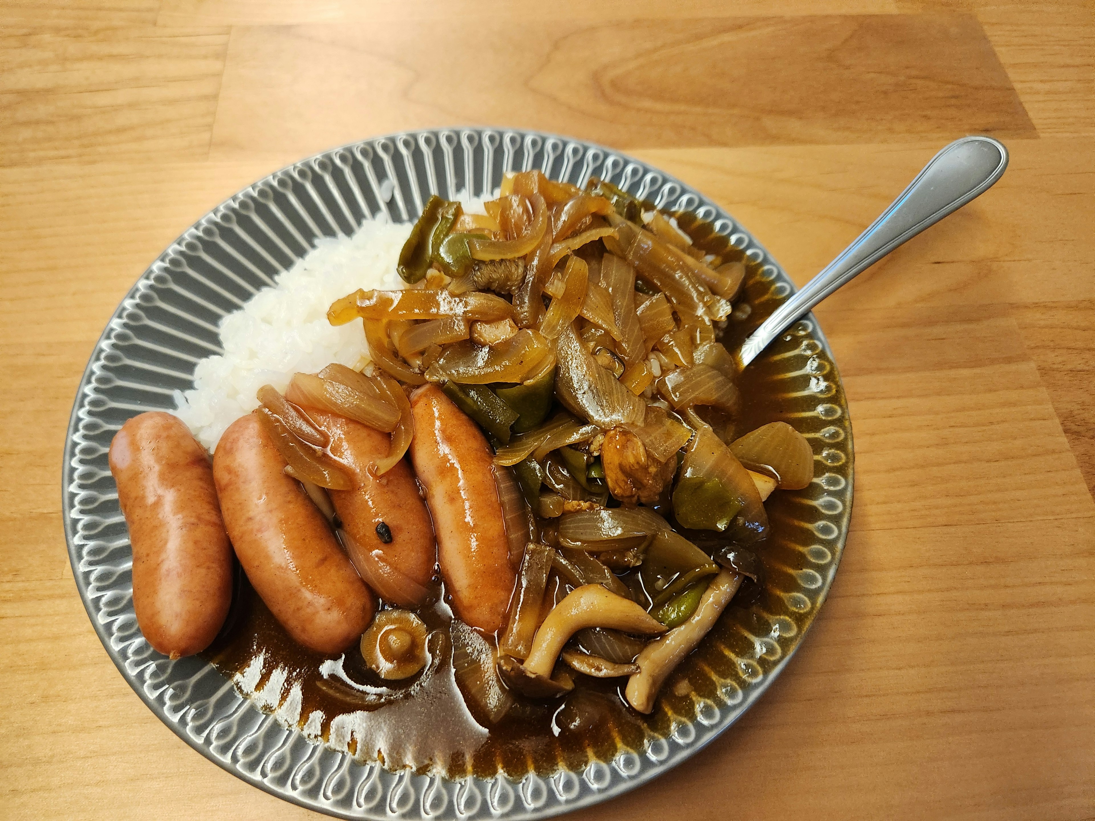 A plate of rice with sausages and stir-fried vegetables