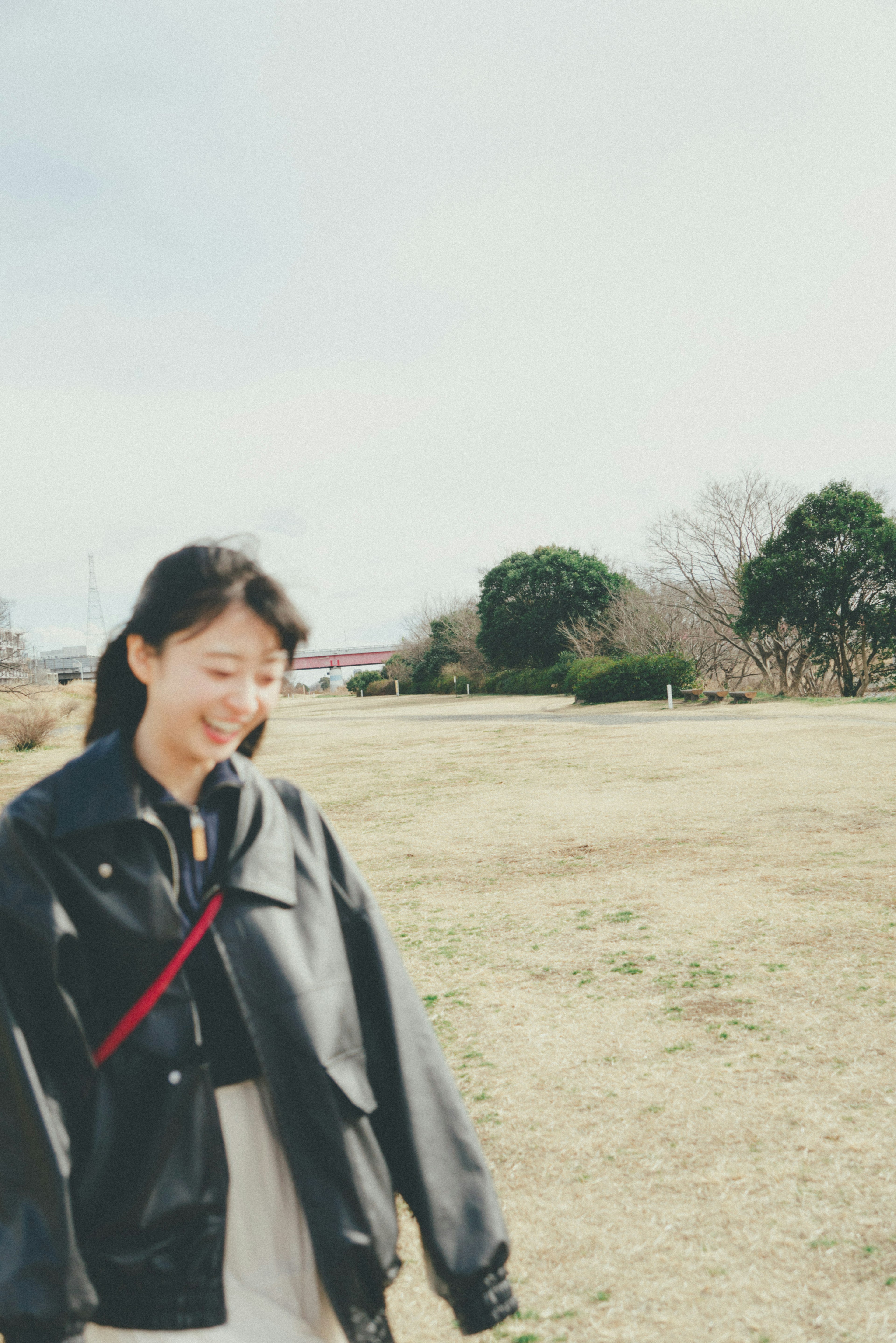 女性が黒いジャケットを着て公園を歩いている風景