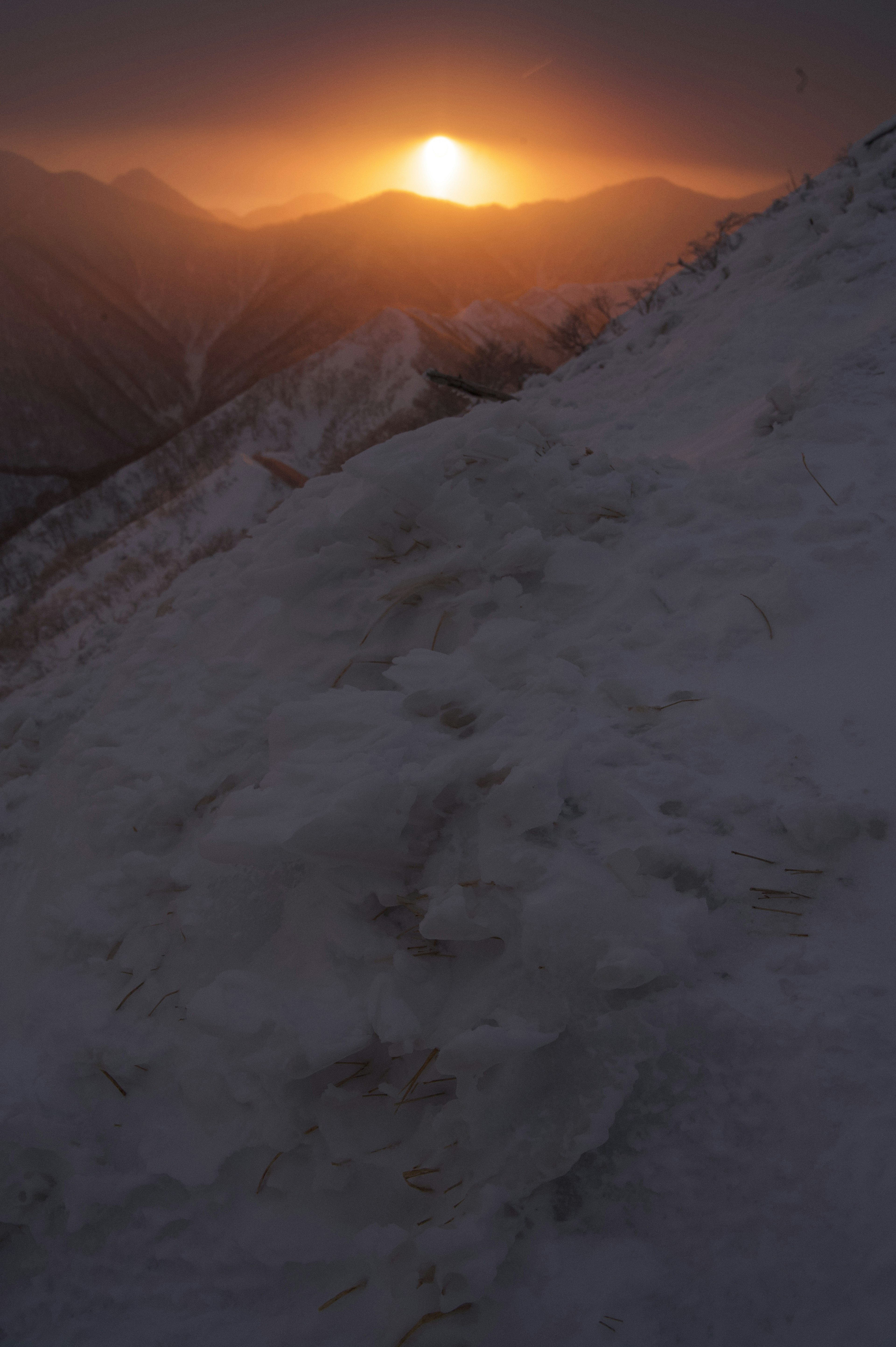 Sonnenuntergang über verschneiten Bergen mit klarem Horizont