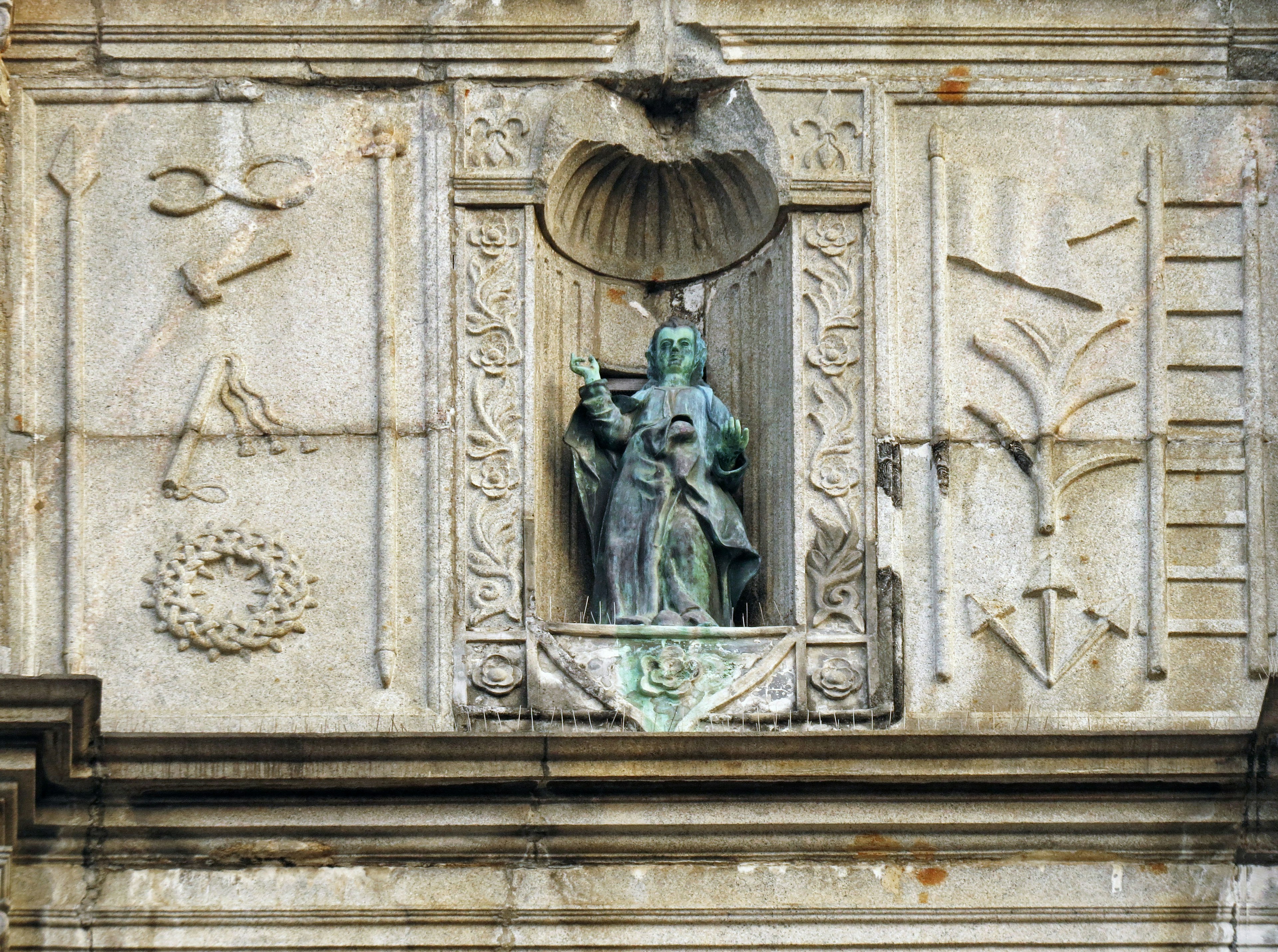 Estatua en una pared de edificio con tallados y decoraciones clásicas