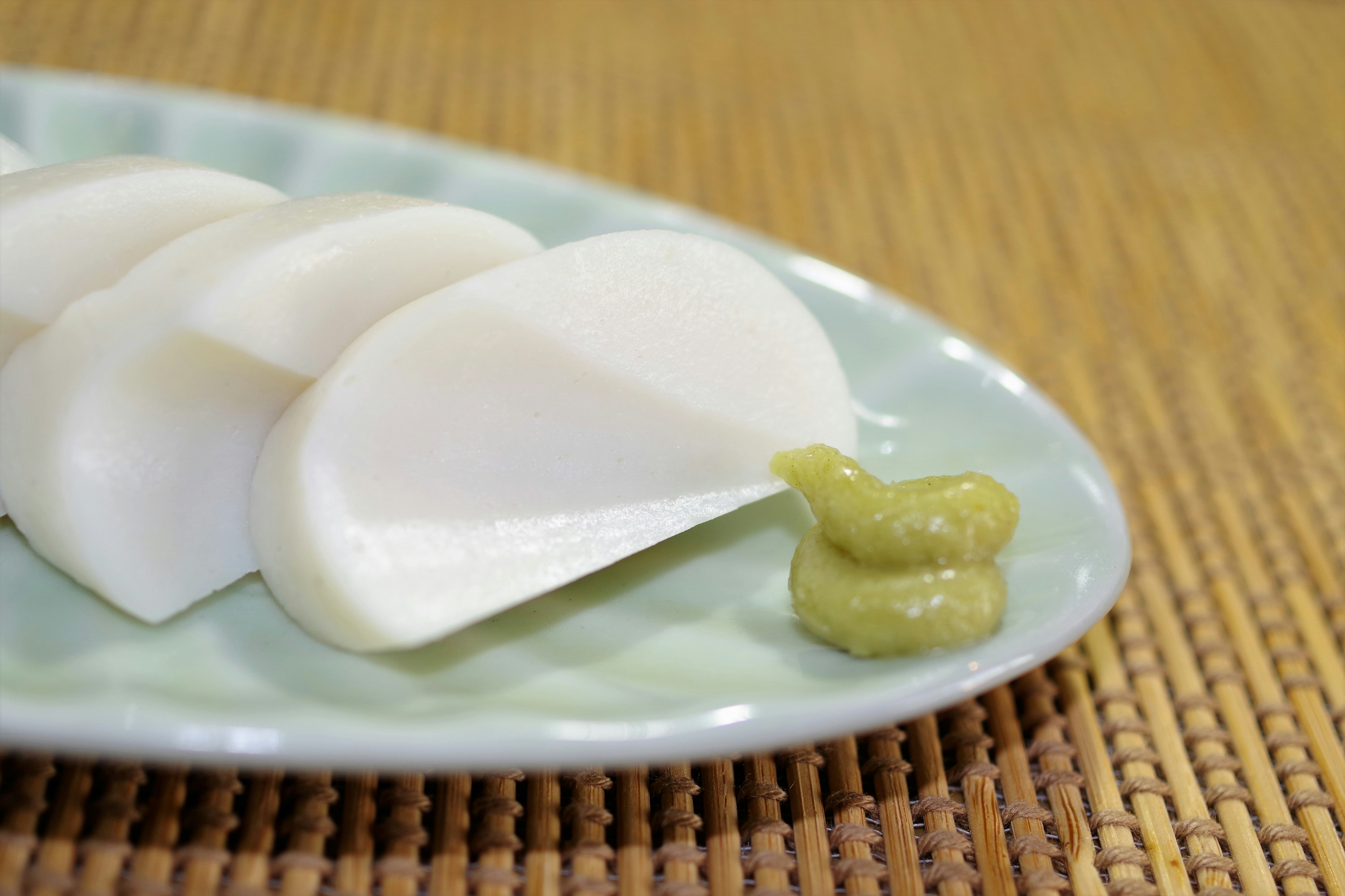 Rábano blanco en rodajas servido con wasabi en un plato