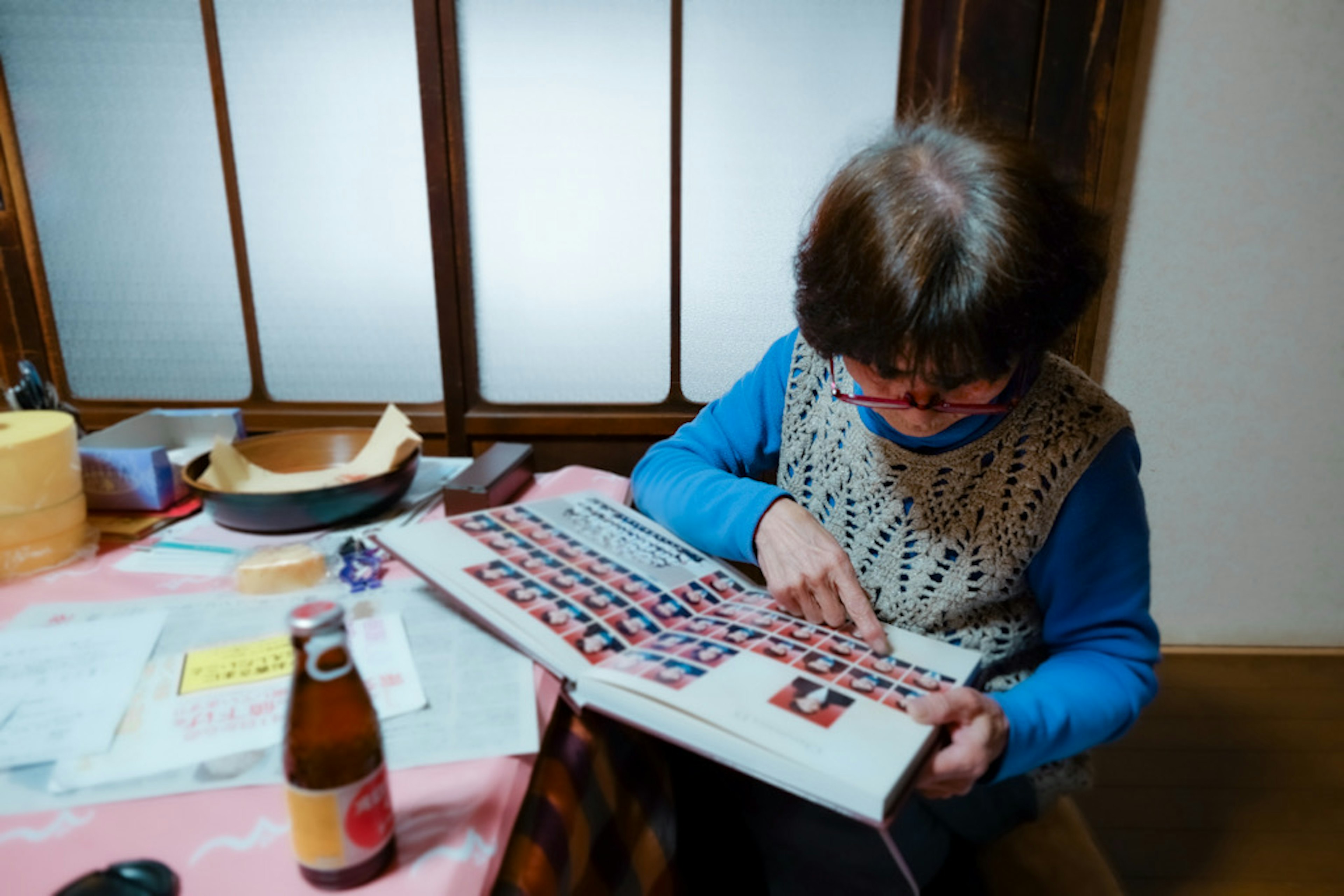 Femme âgée assise à une table lisant un magazine