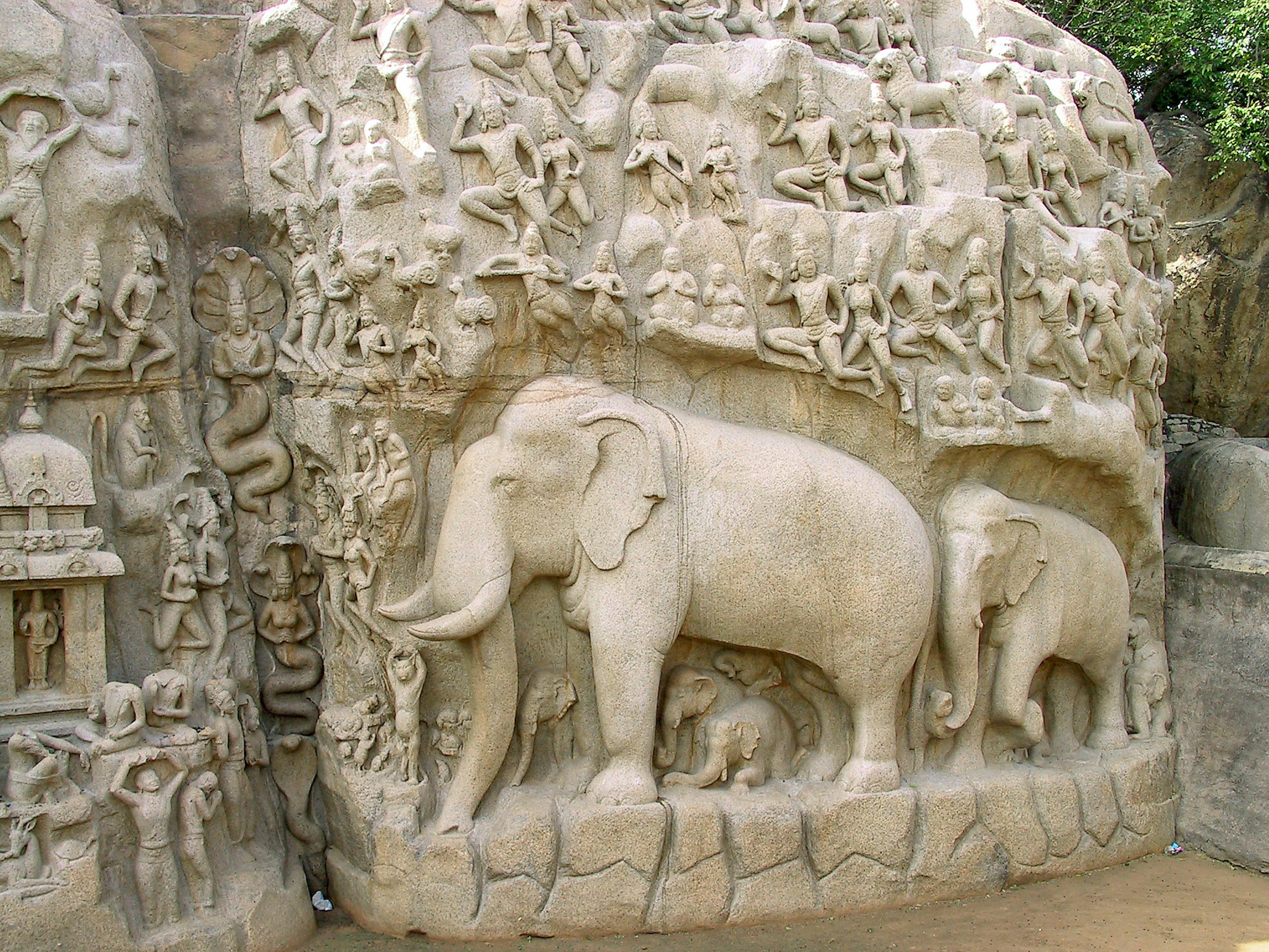 Relief sculpture of elephants on a stone wall surrounded by various animal and human figures