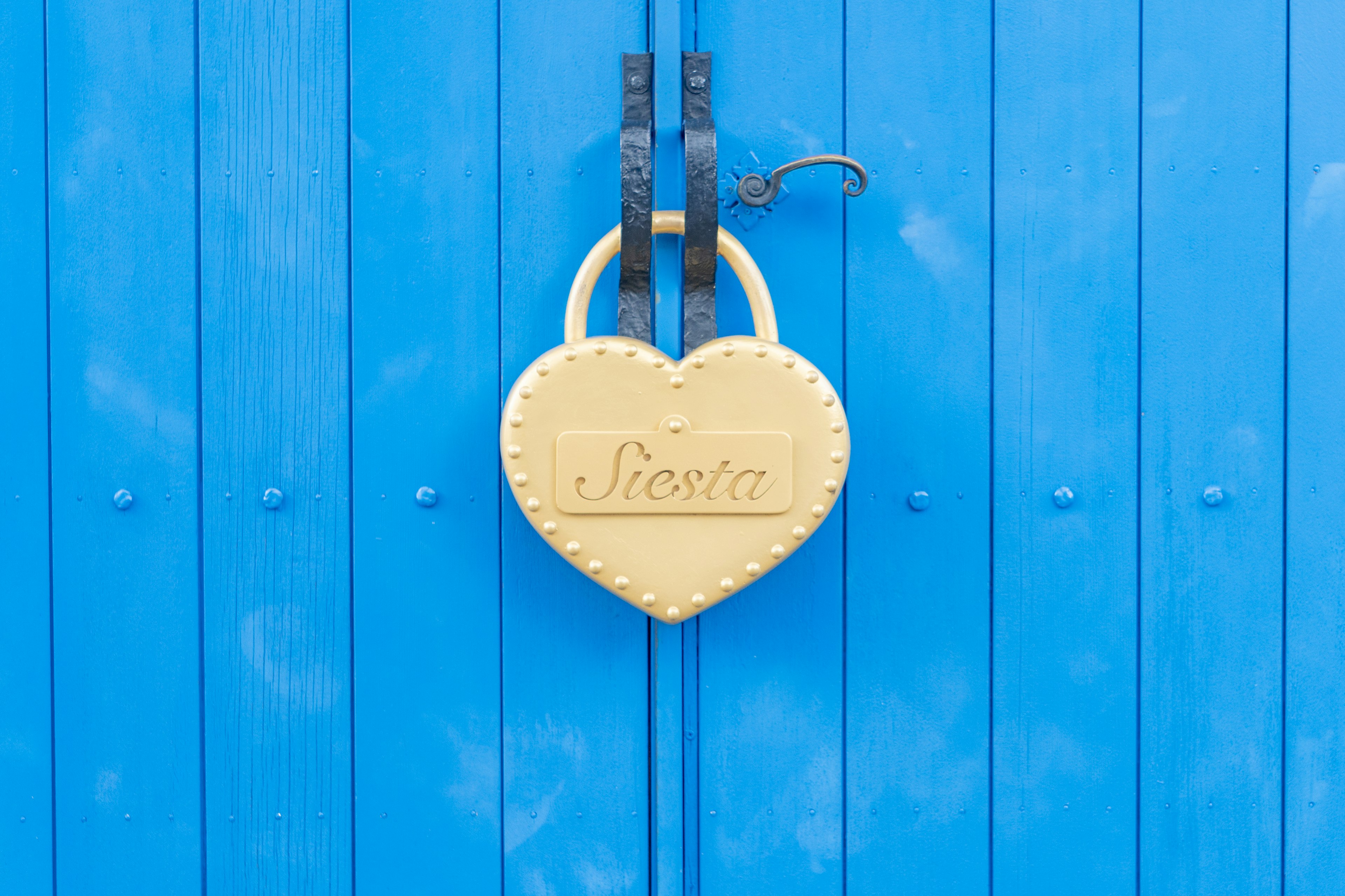 Un lucchetto a forma di cuore dorato appeso a una porta blu