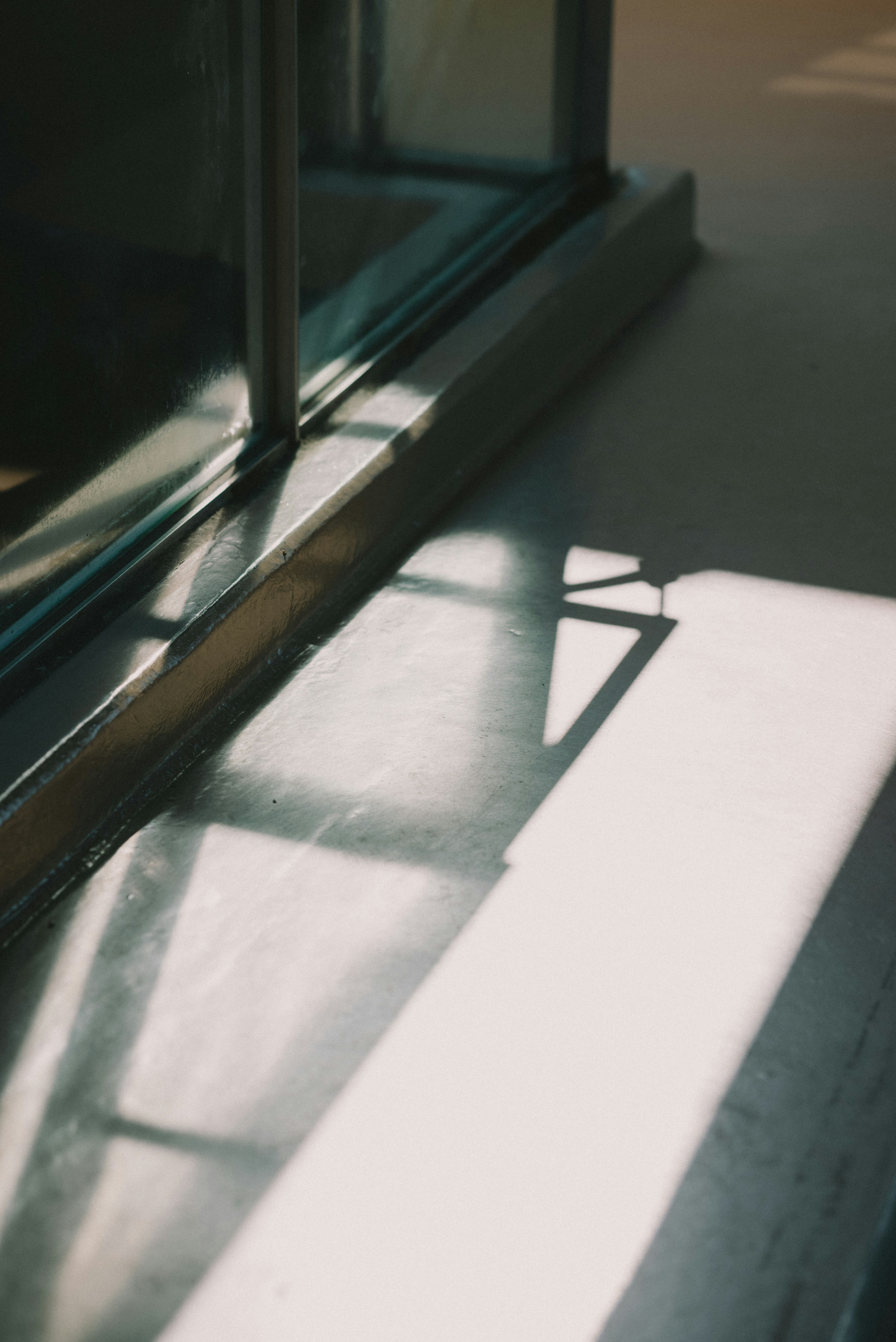 Sonnenlicht, das Schatten auf den Boden neben einem Fenster wirft