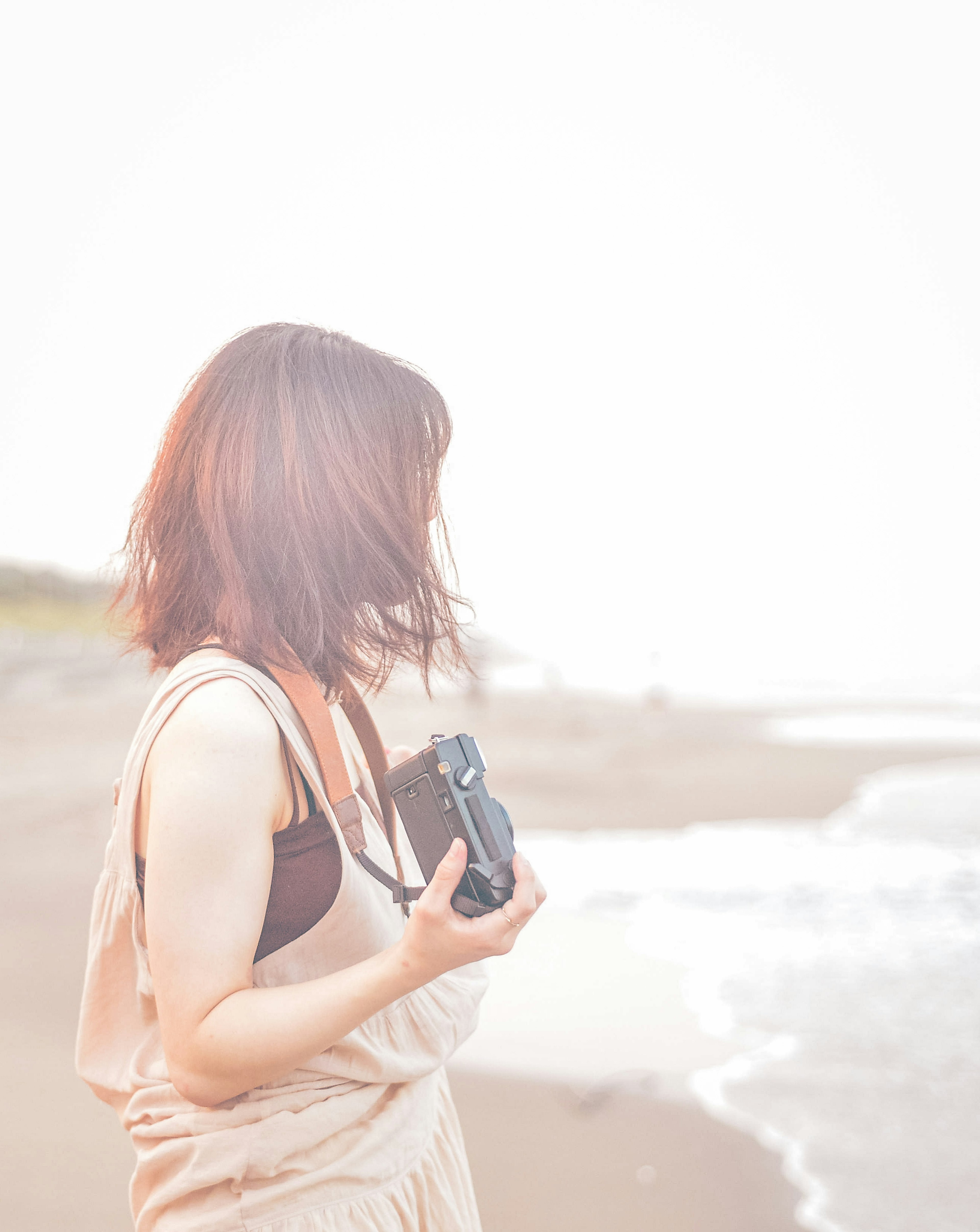 Frau mit einer Kamera am Strand