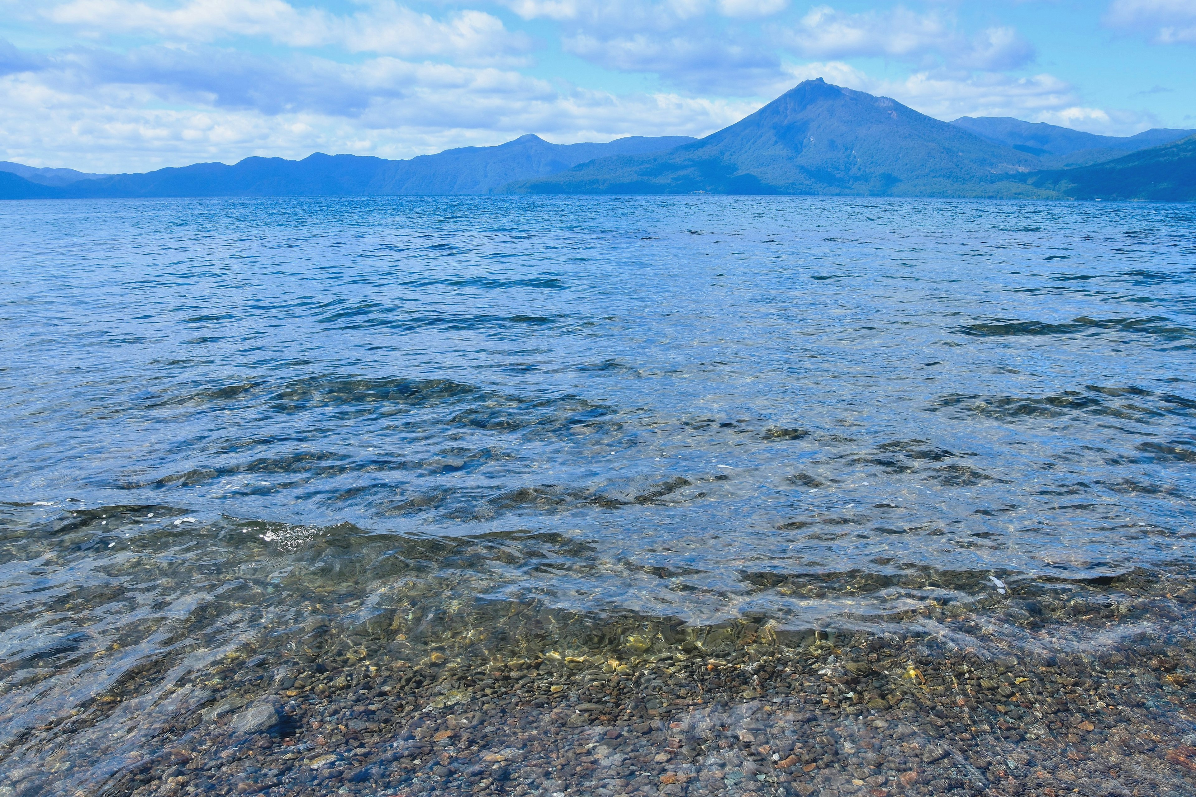 Vista panoramica di un lago blu con onde leggere e una montagna in lontananza