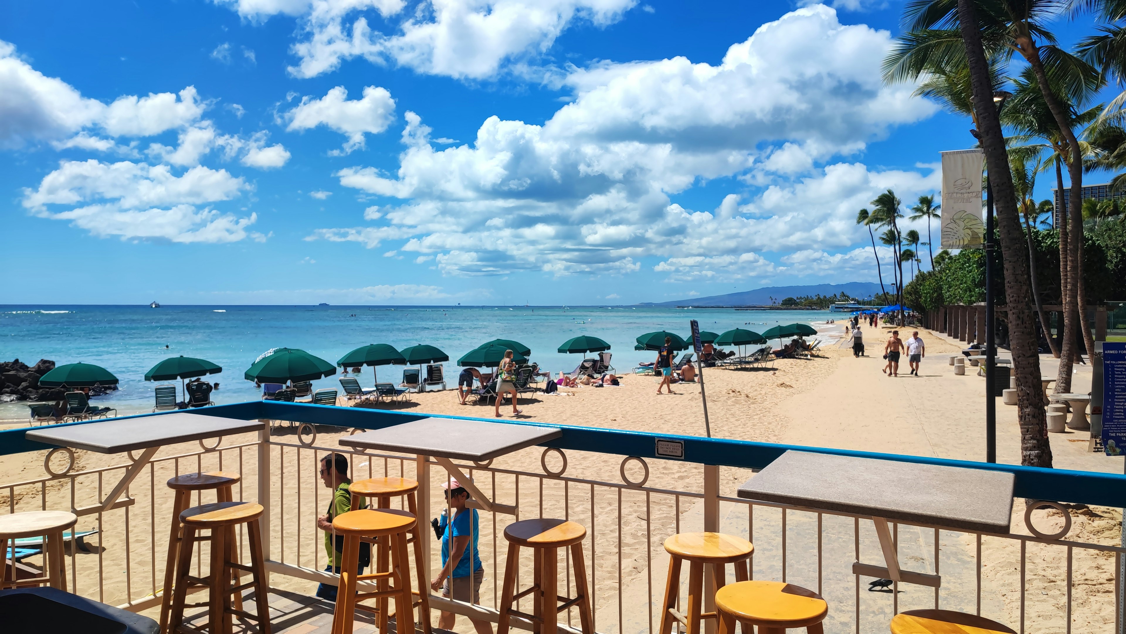 Malersicher Strandblick mit blauem Ozean und weißem Sand Sonnenschirmen und Palmen