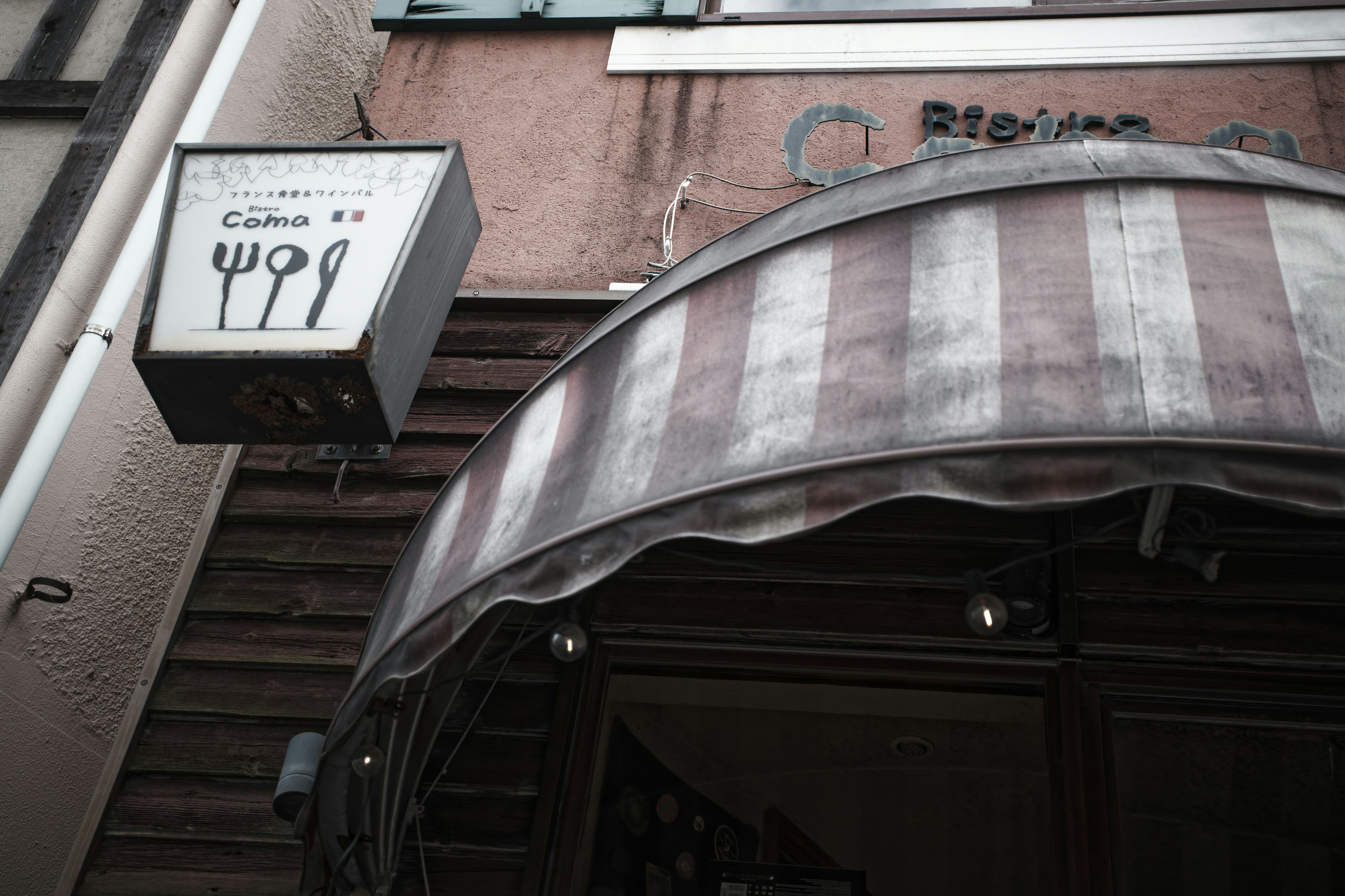 Panneau de restaurant avec des couverts et un auvent rayé