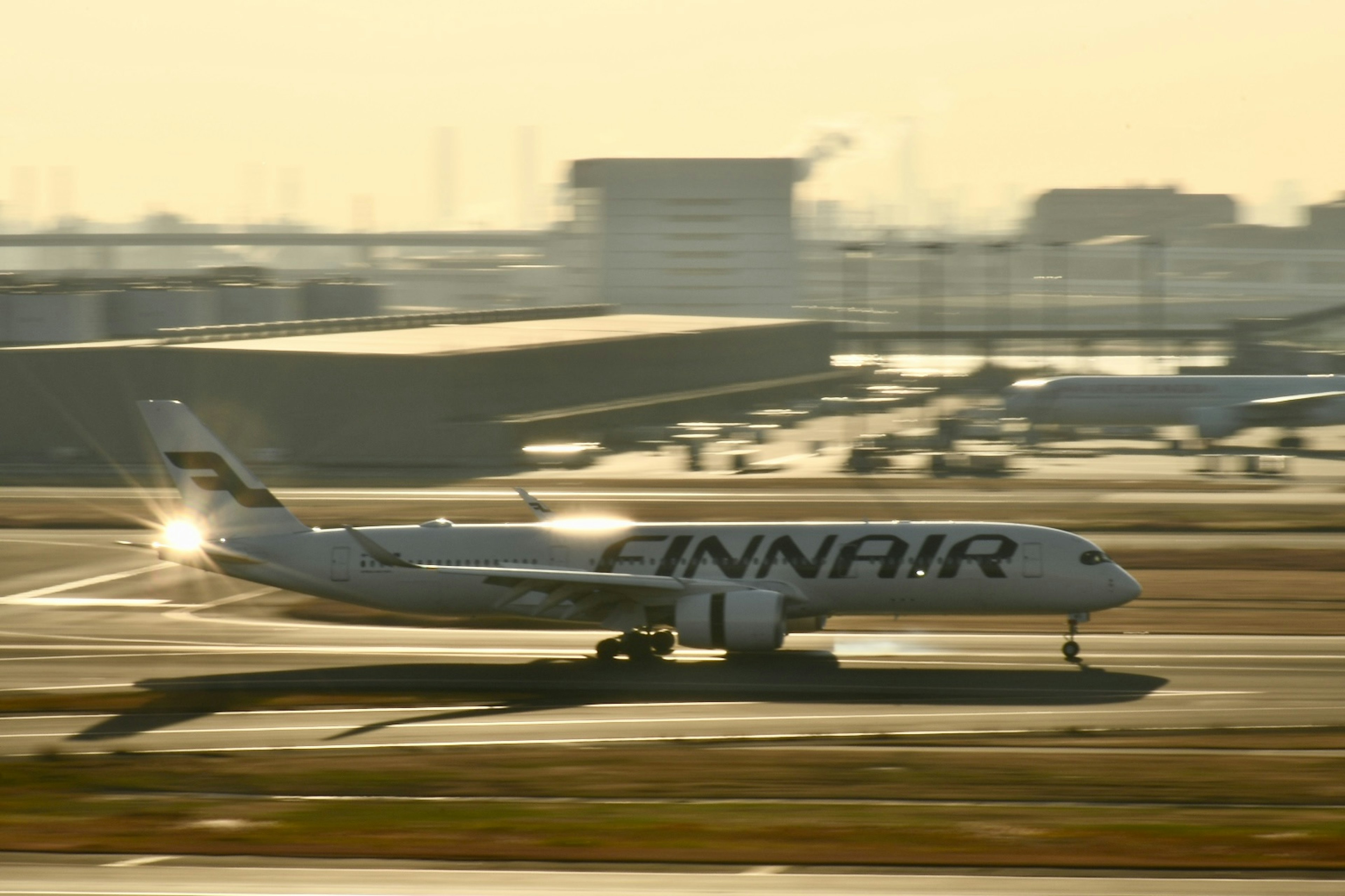 Avión de pasajeros de Finnair rodando en la pista con un atardecer de fondo