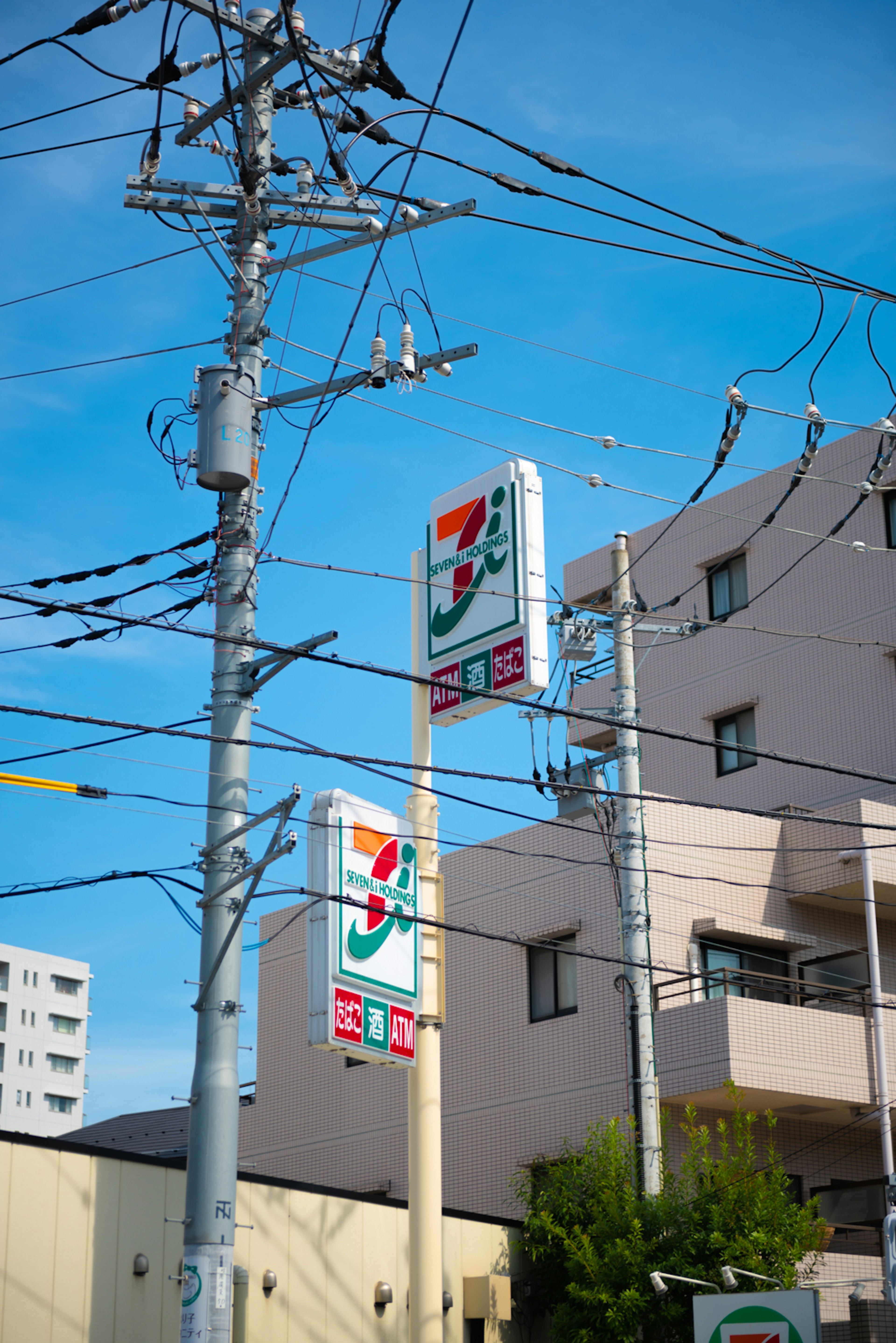 ป้าย 7-Eleven ใต้ท้องฟ้าสีฟ้าพร้อมสายไฟ