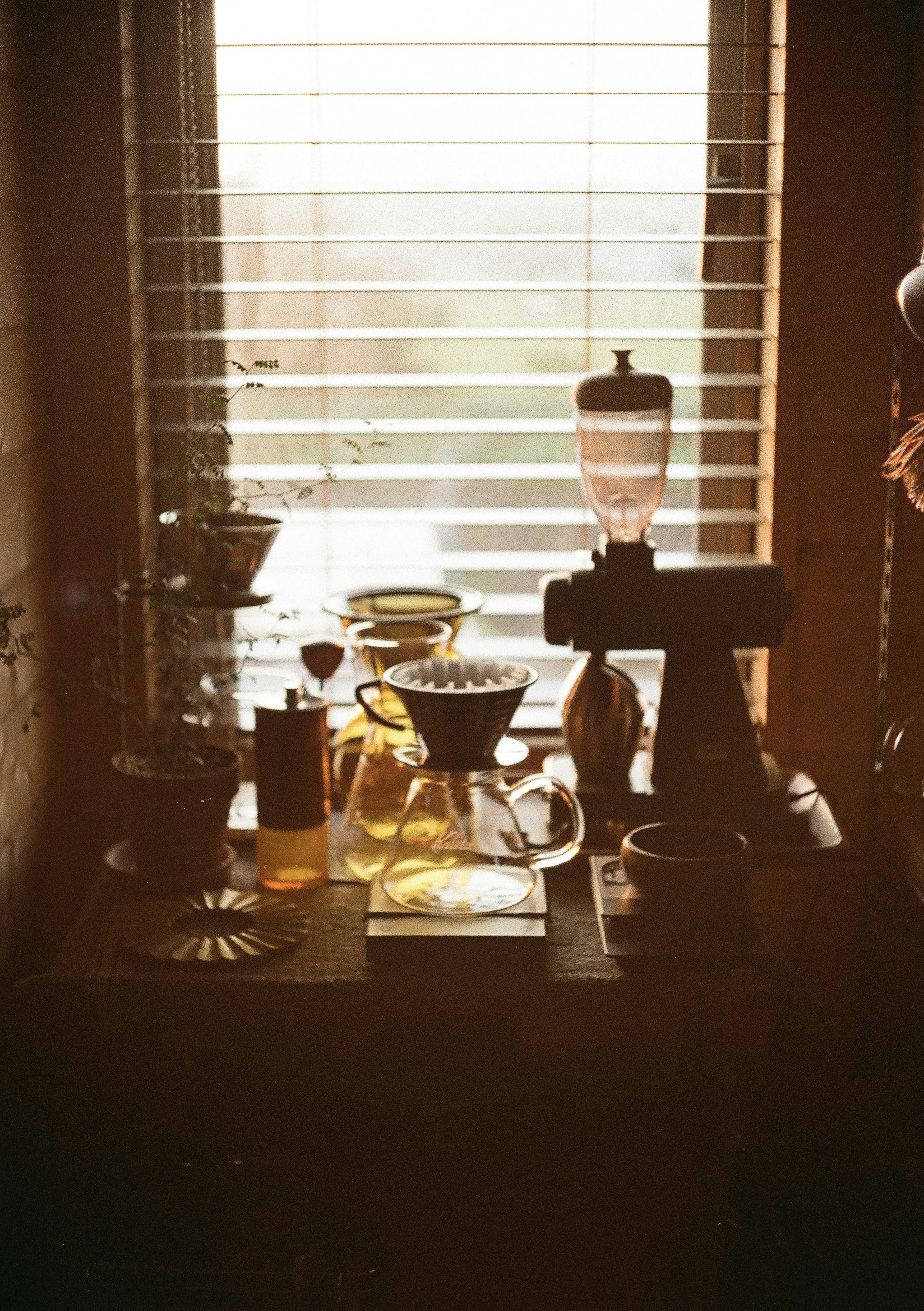 A cozy window scene featuring coffee equipment and glass containers