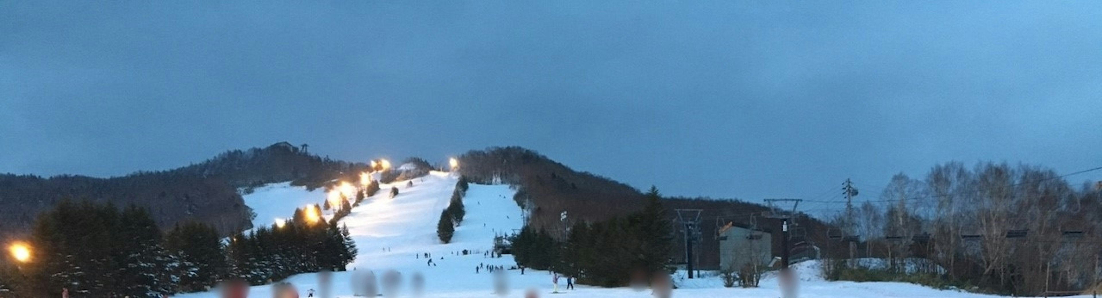 Vista nocturna de una estación de esquí cubierta de nieve con telesillas iluminados