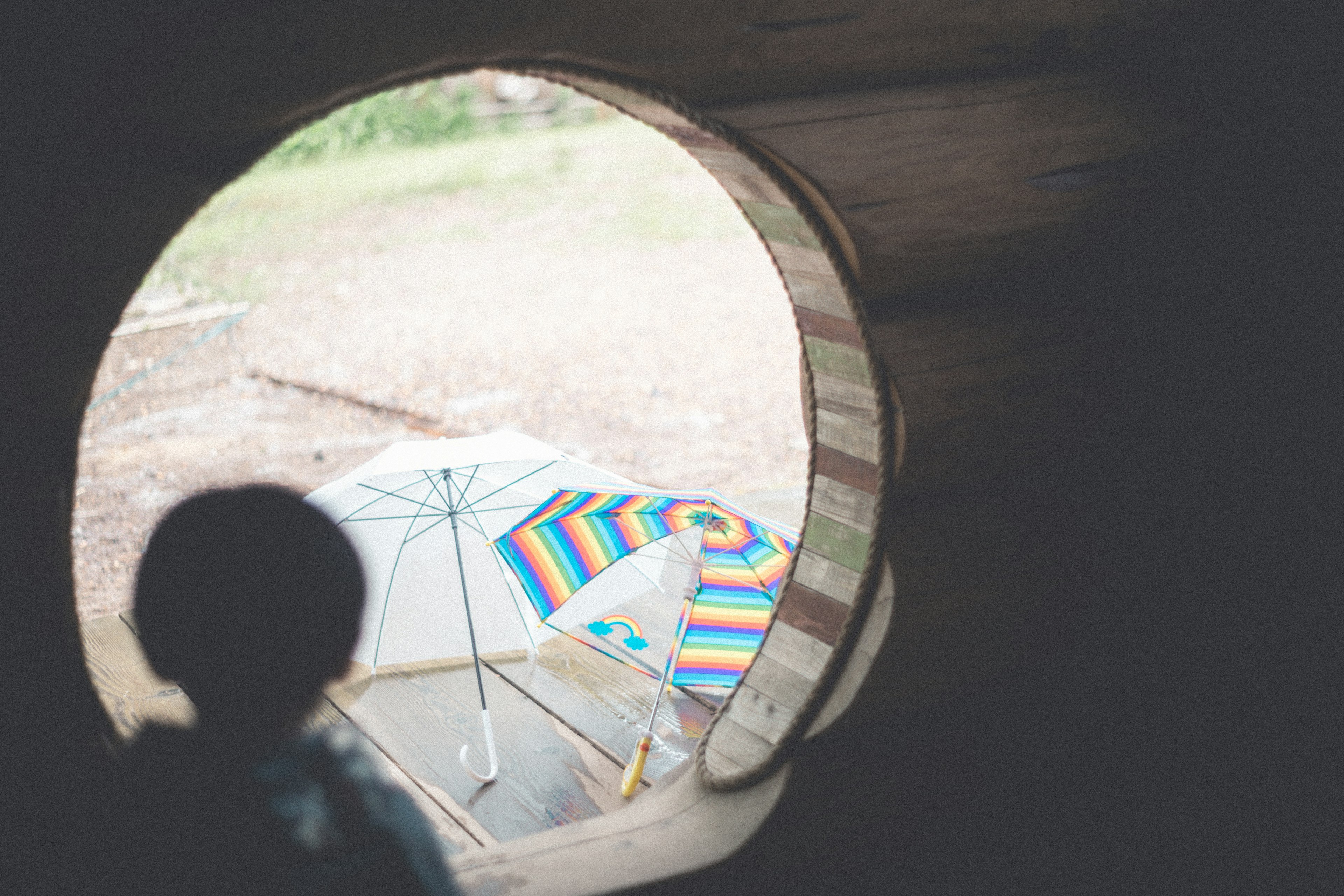 Parapluie coloré et tapis de plage vus à travers une fenêtre ronde