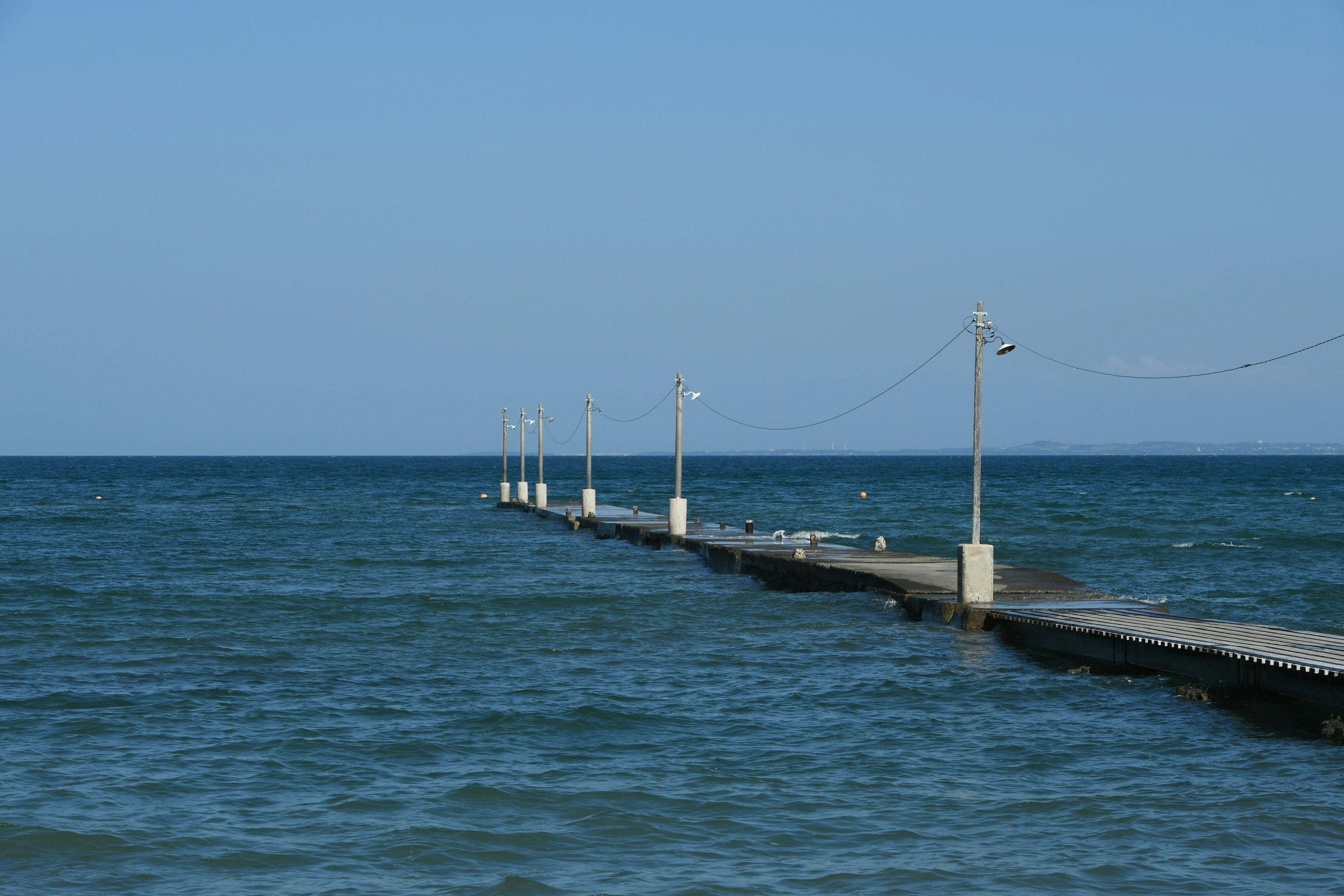 Pier extending into the blue ocean under a clear sky