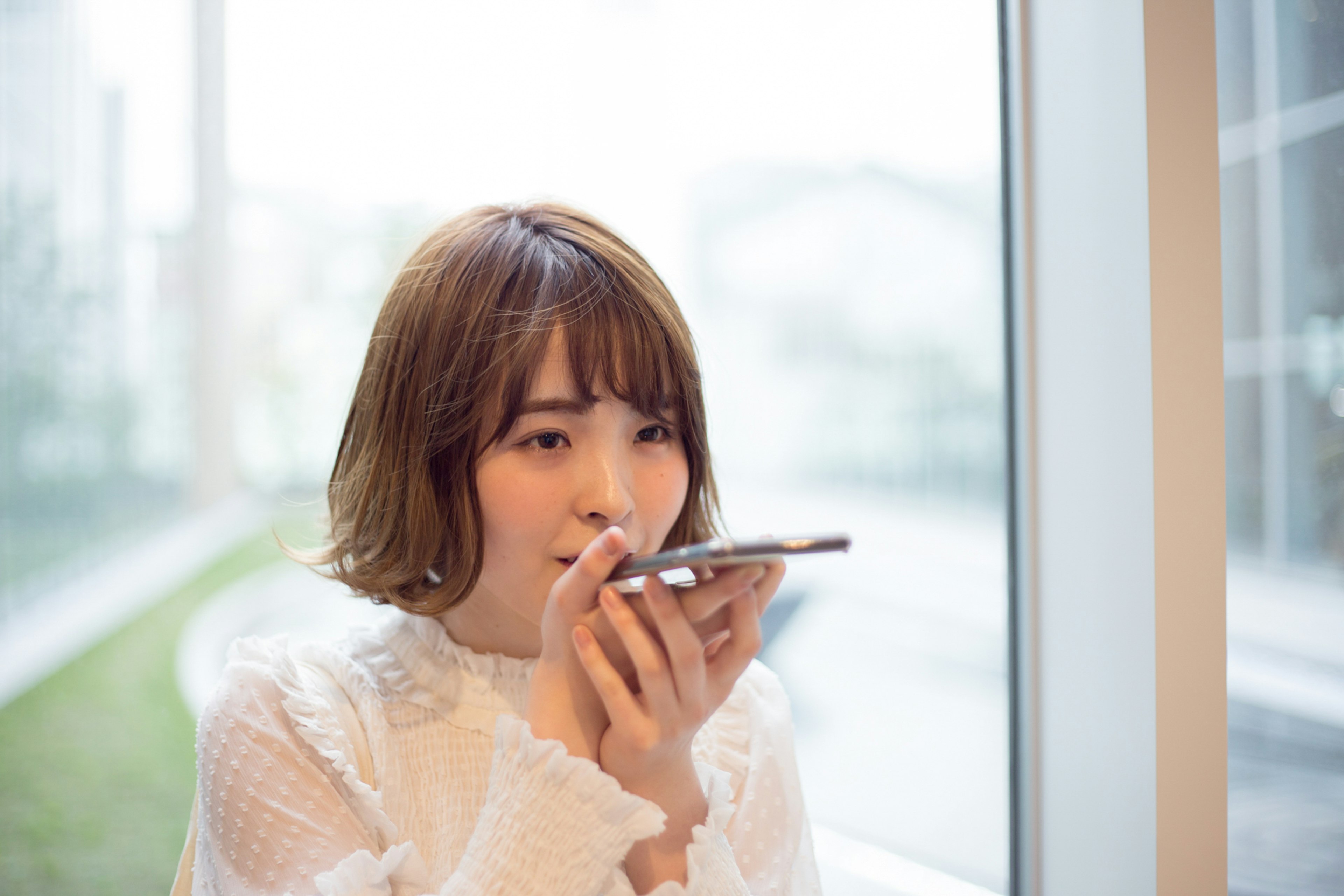 Una mujer usando un teléfono inteligente junto a la ventana