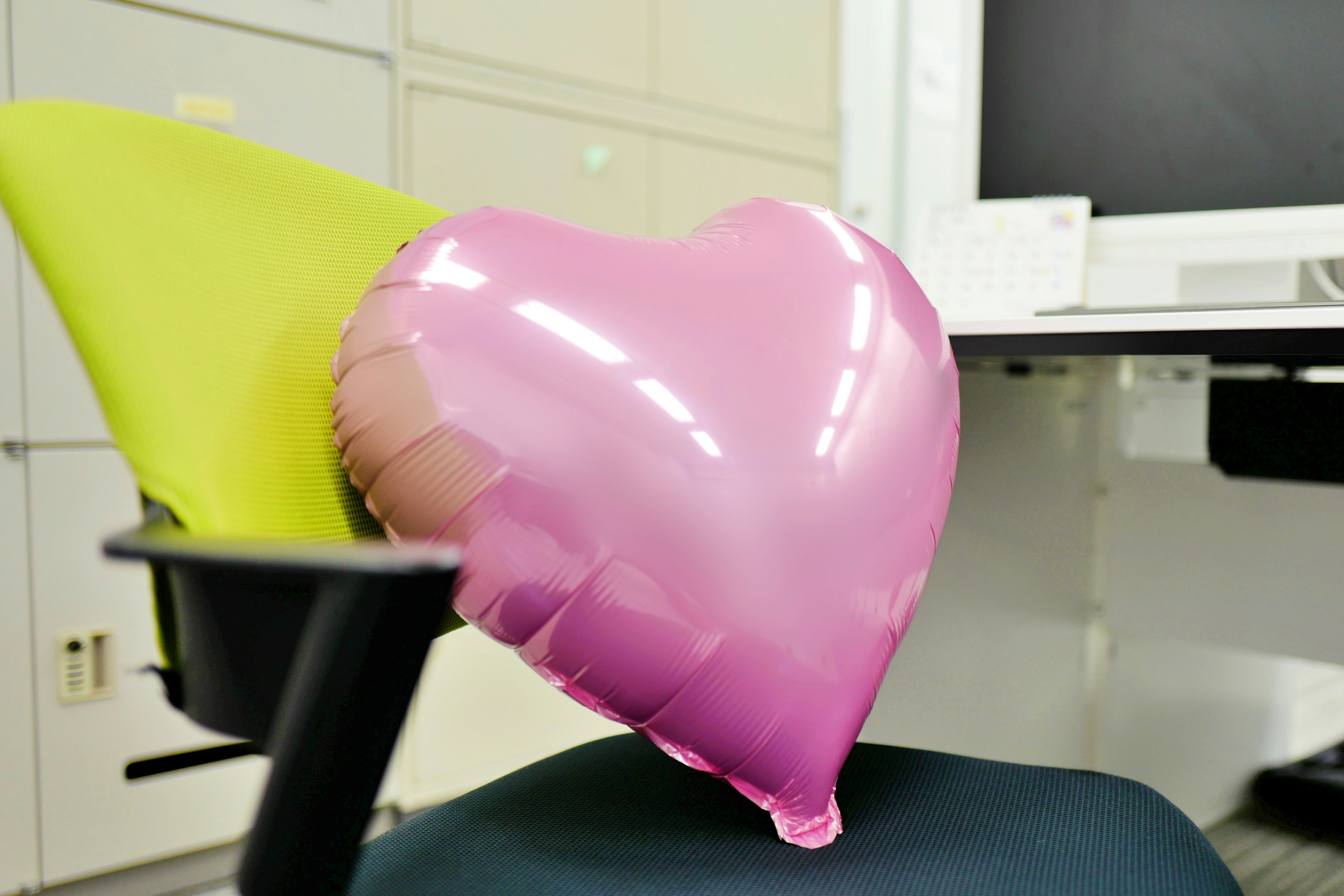 Heart-shaped pink balloon resting on a chair