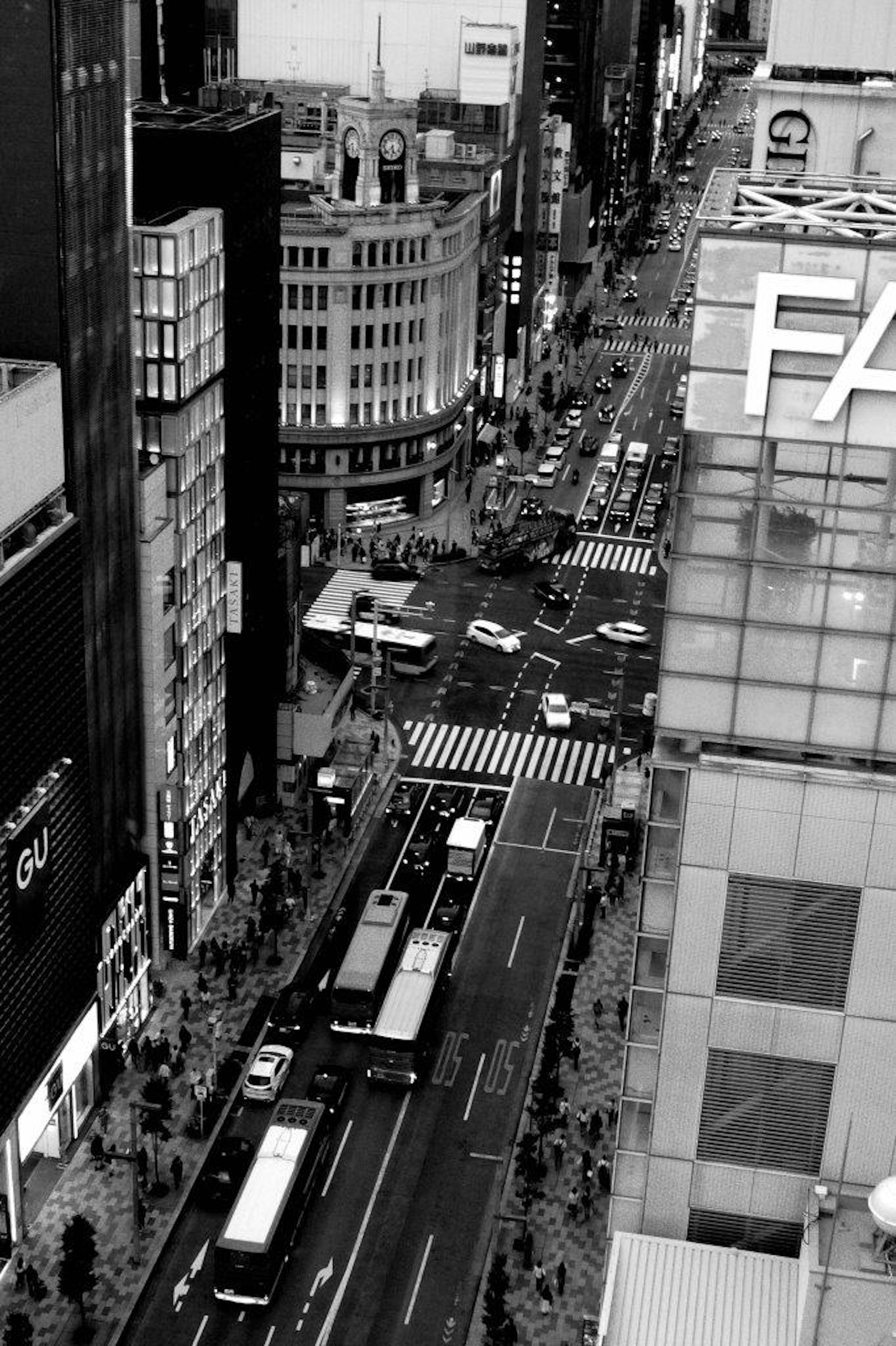 高層ビルの間から見える繁華街のモノクロ写真