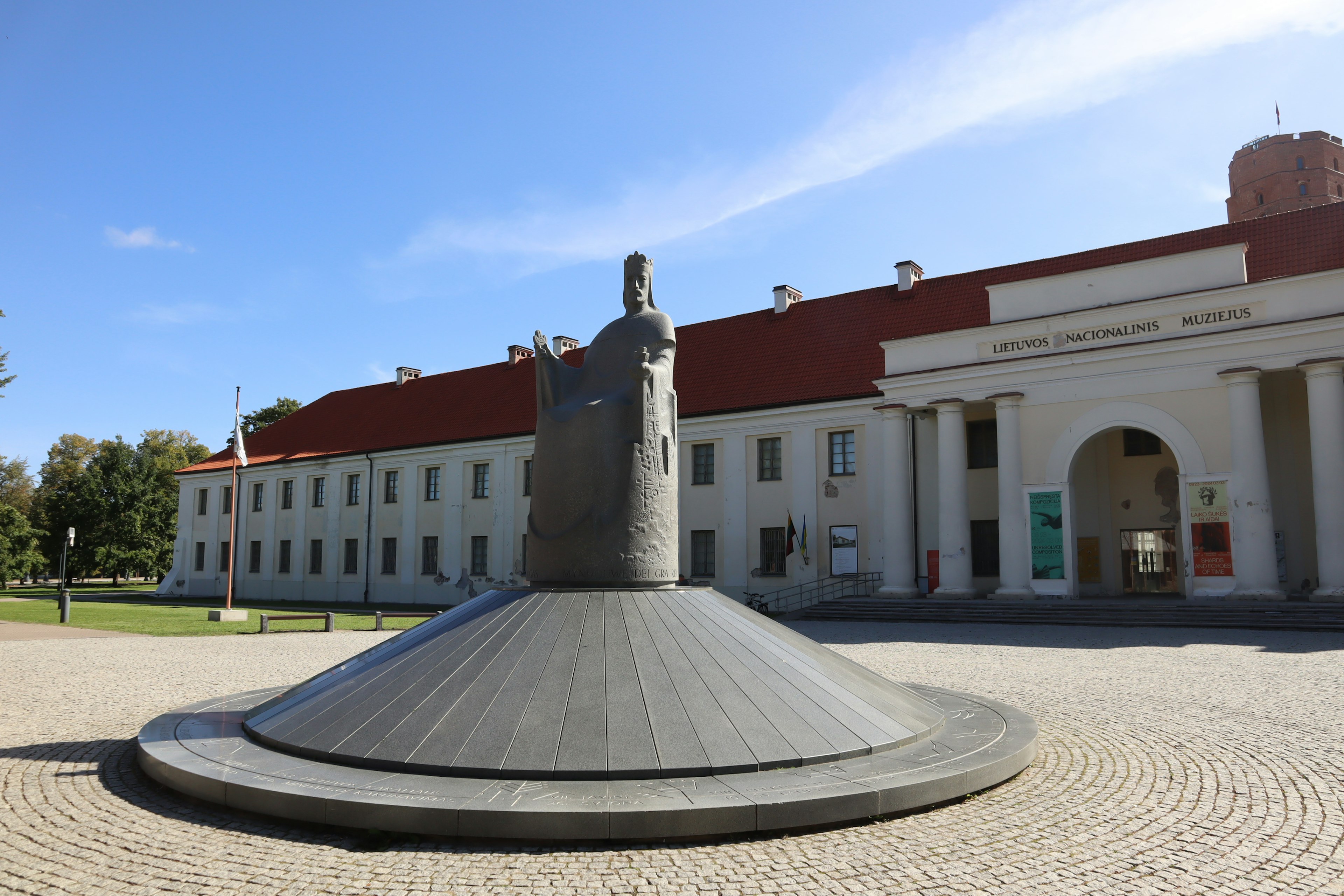 Statue on a circular pedestal in front of a historic building