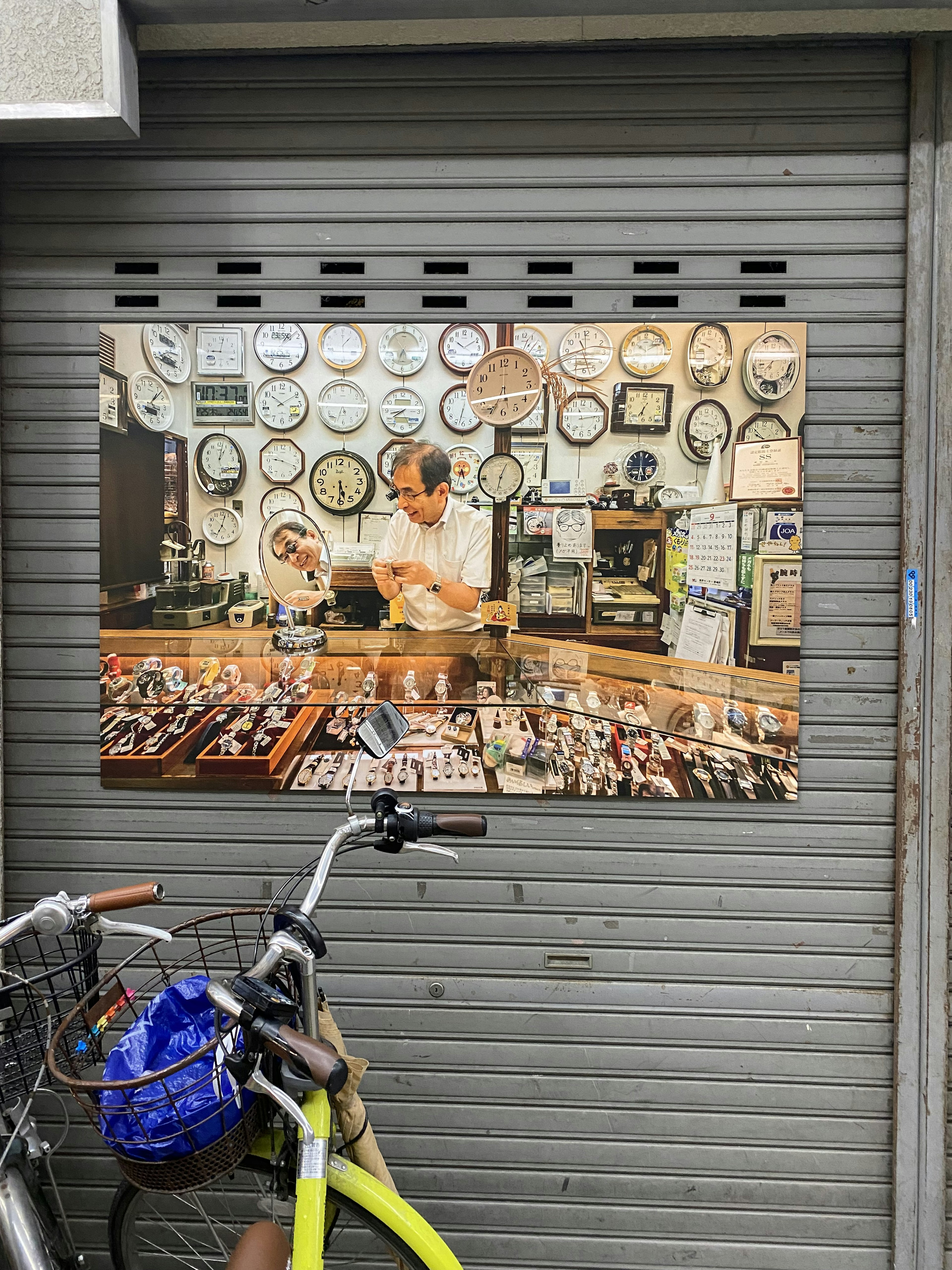 Exterior of a shop displaying watches and jewelry with a shopkeeper