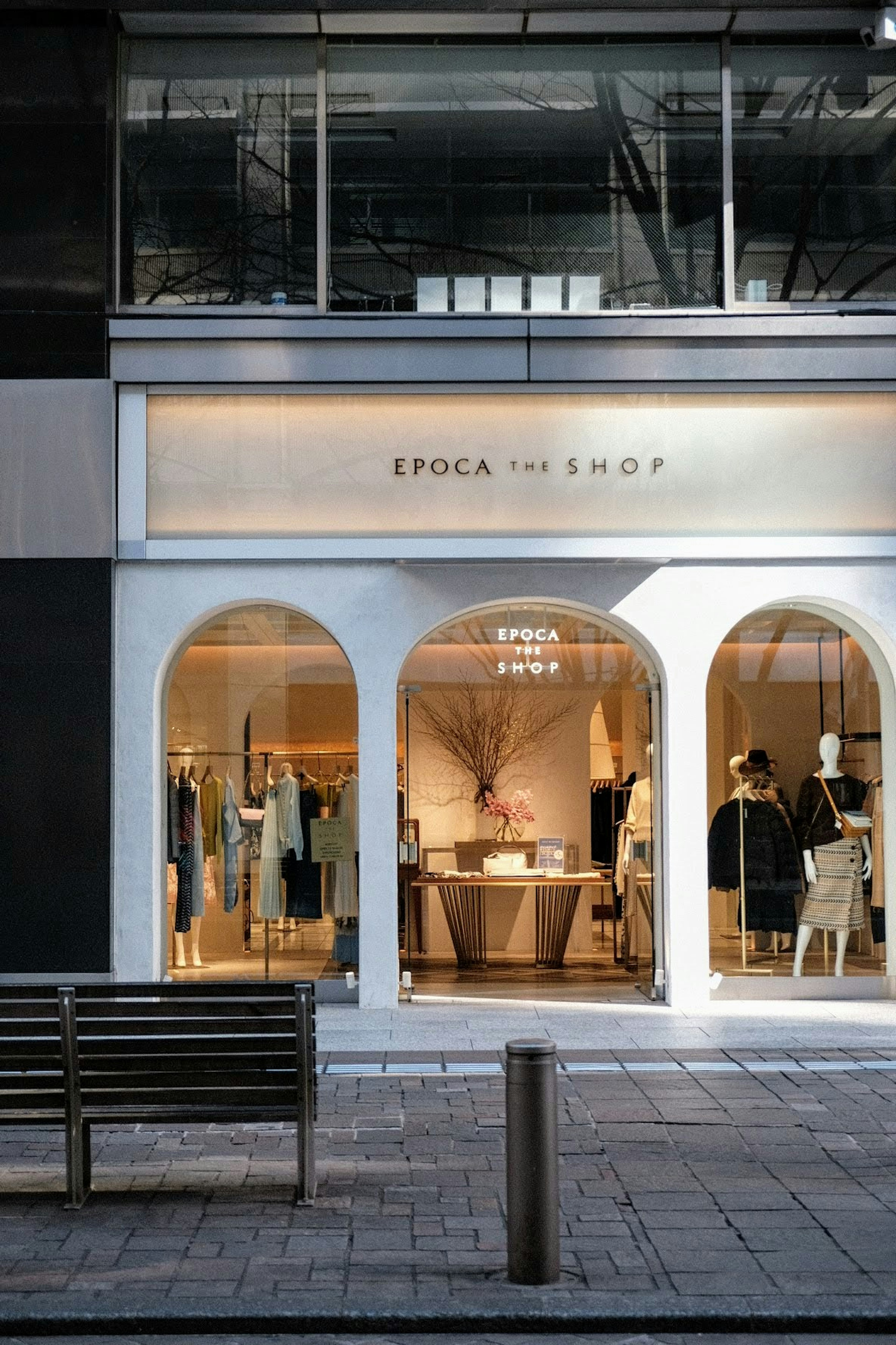 Exterior of a fashion boutique with white arch windows and elegant display