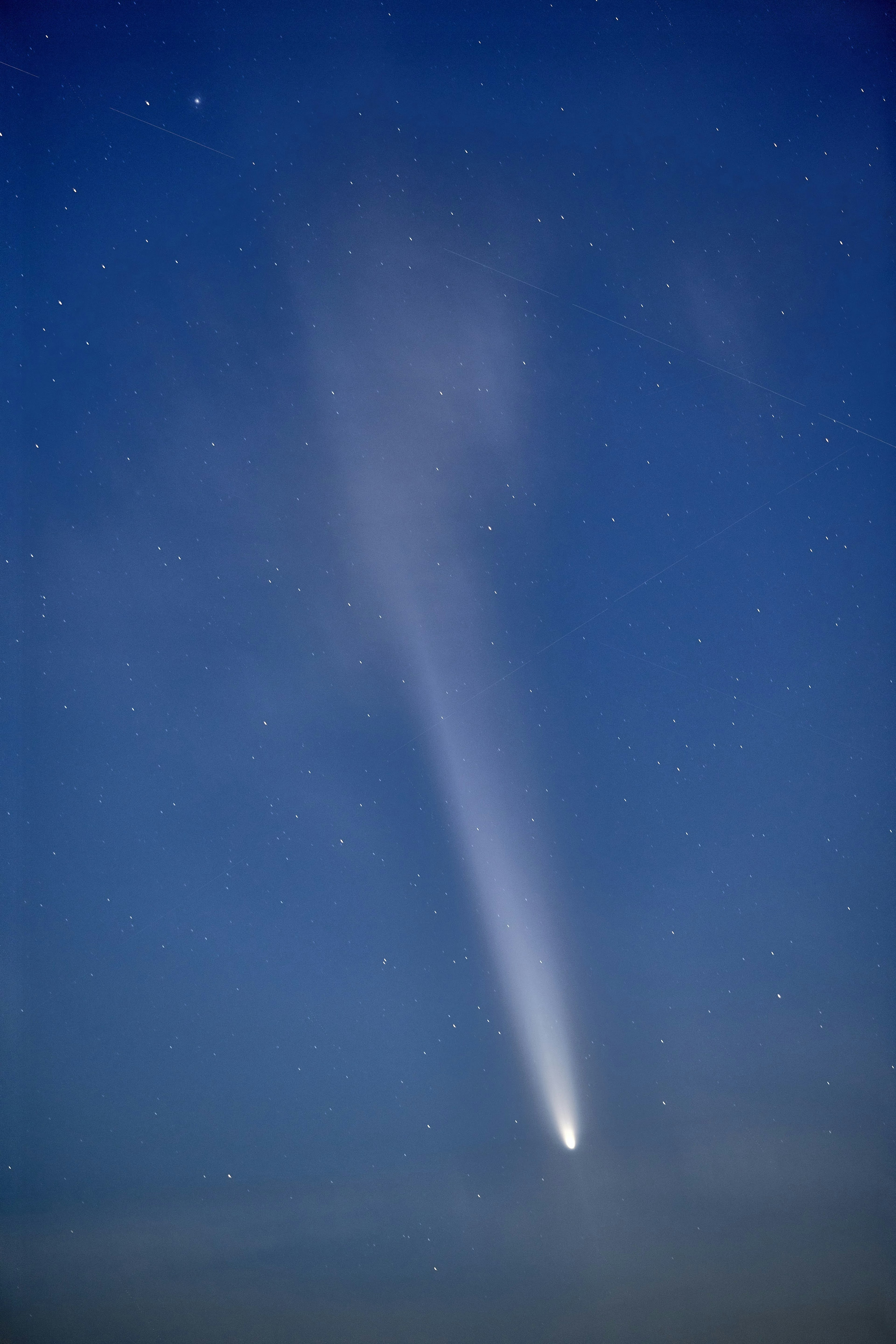 A bright comet trailing through the night sky filled with stars