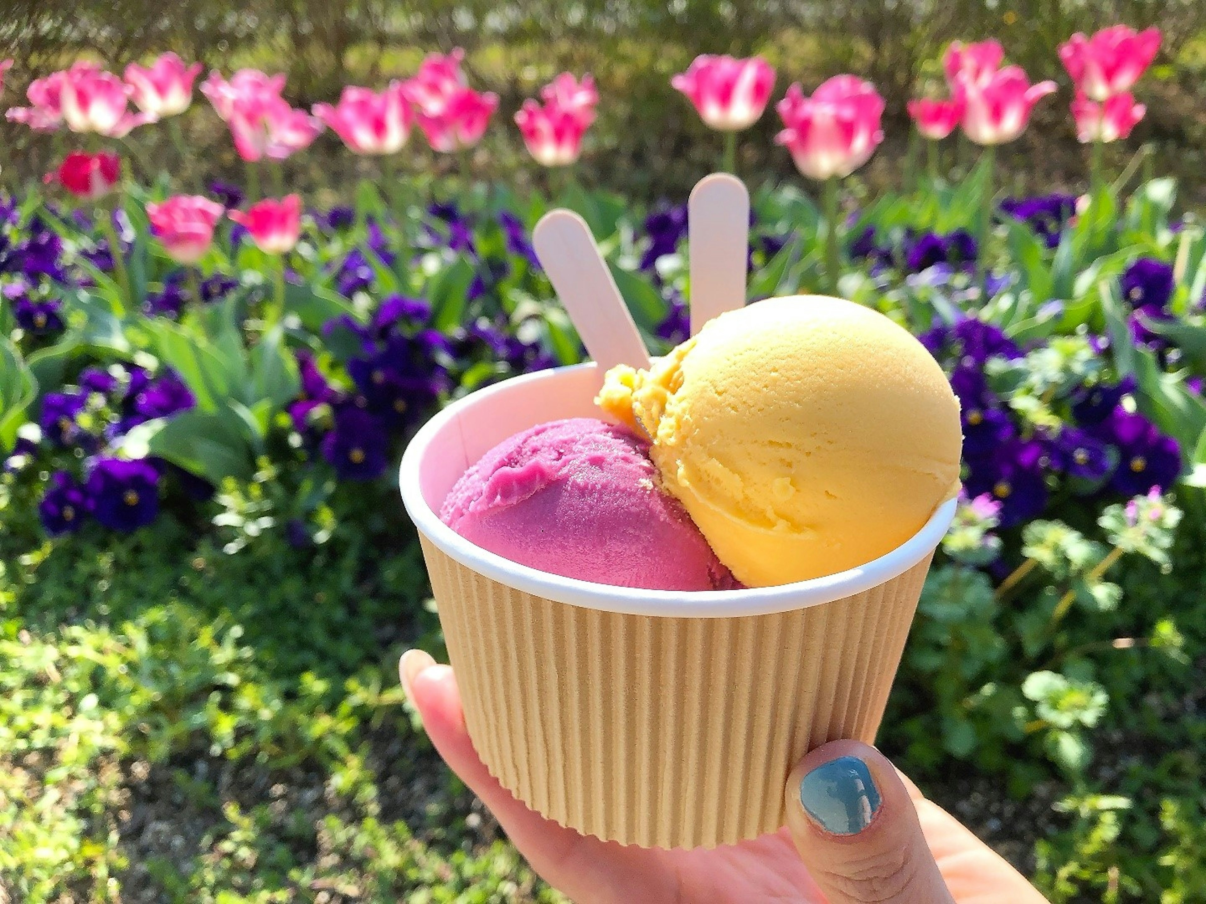 Un pot de crème glacée rose et jaune avec des fleurs colorées en arrière-plan