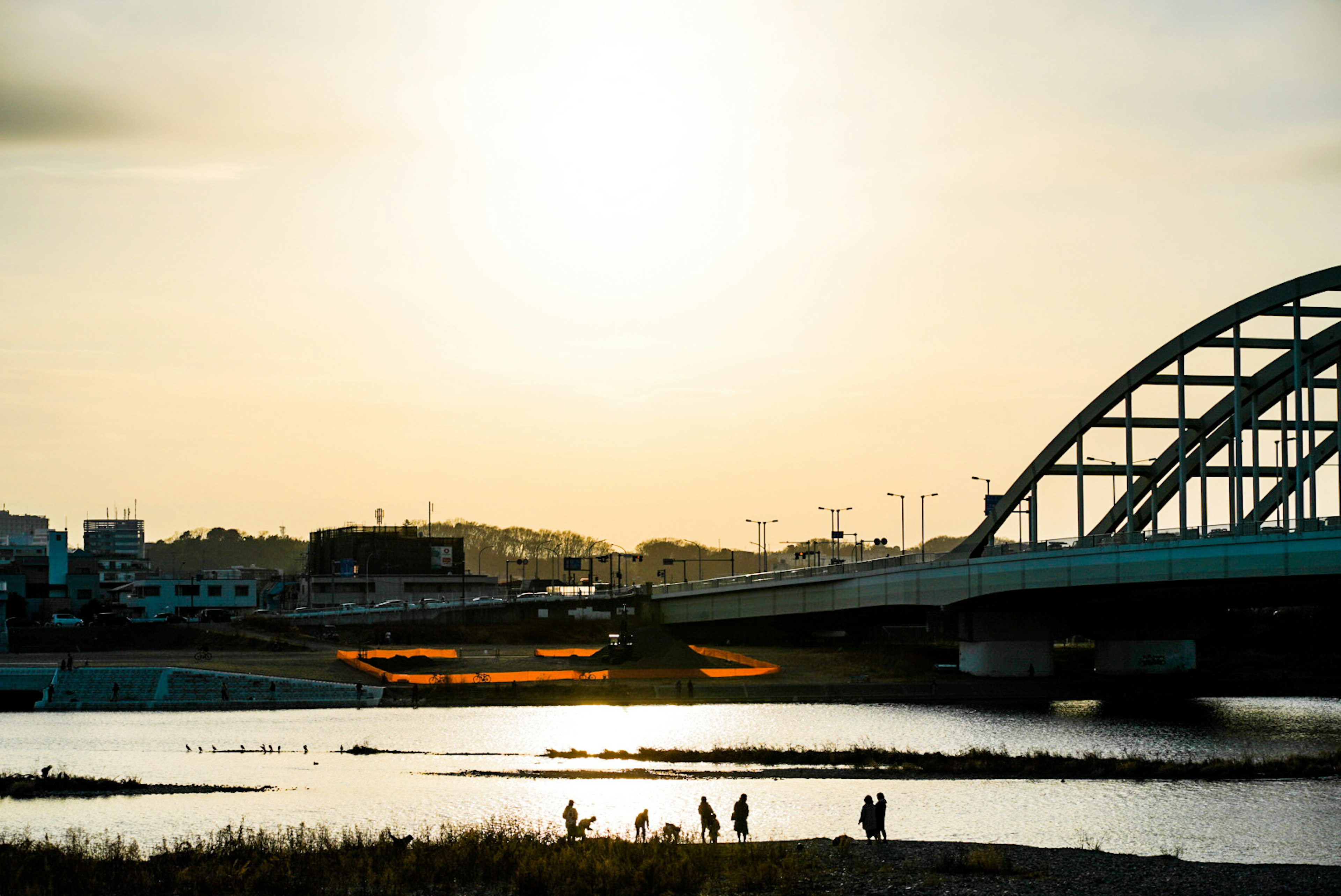 夕日を背景にした橋と川の景色人々が水辺に集まる