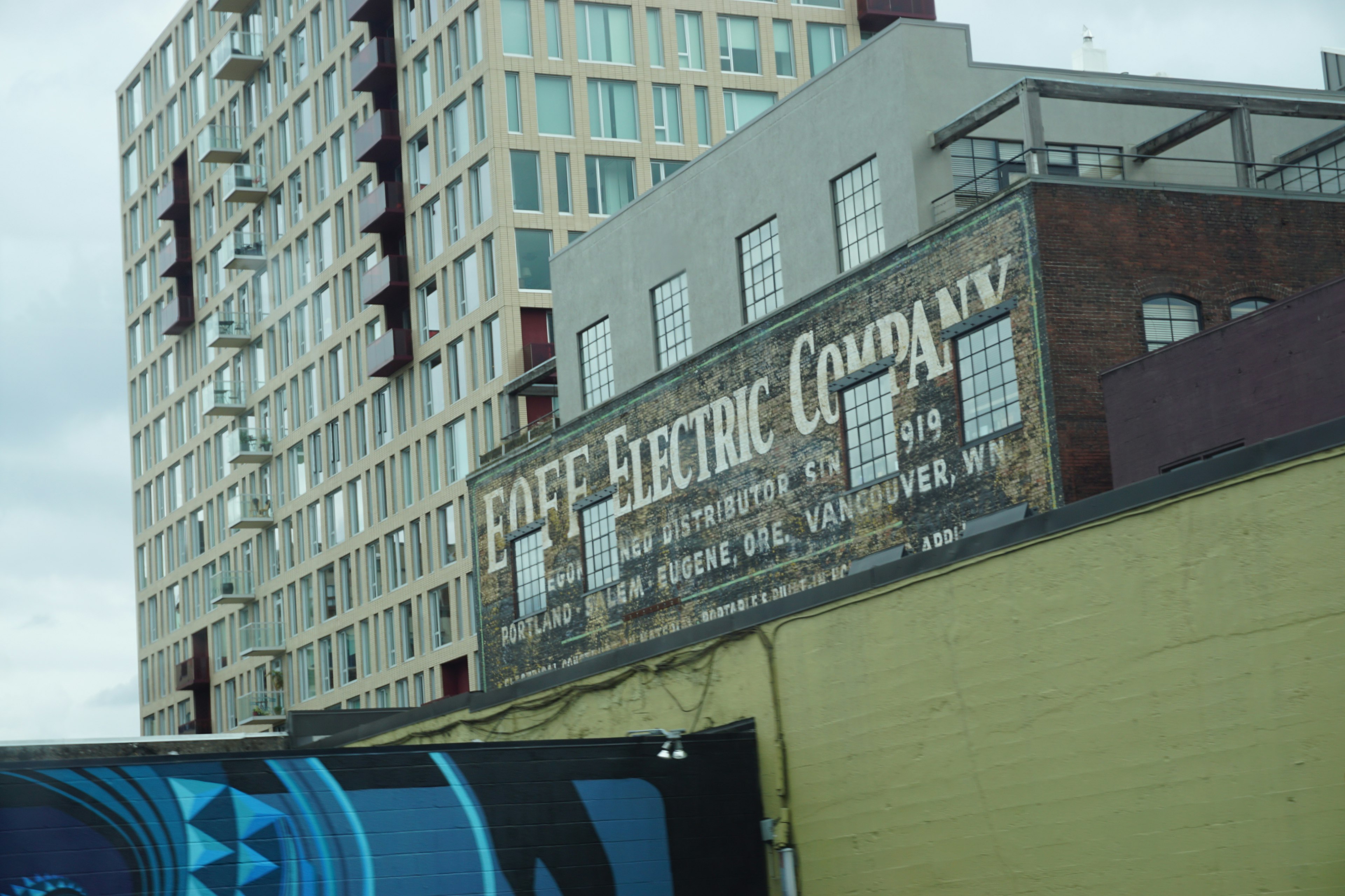 Vintage-Schild einer Elektrizitätsgesellschaft an einer Wand mit einem modernen Gebäude im Hintergrund