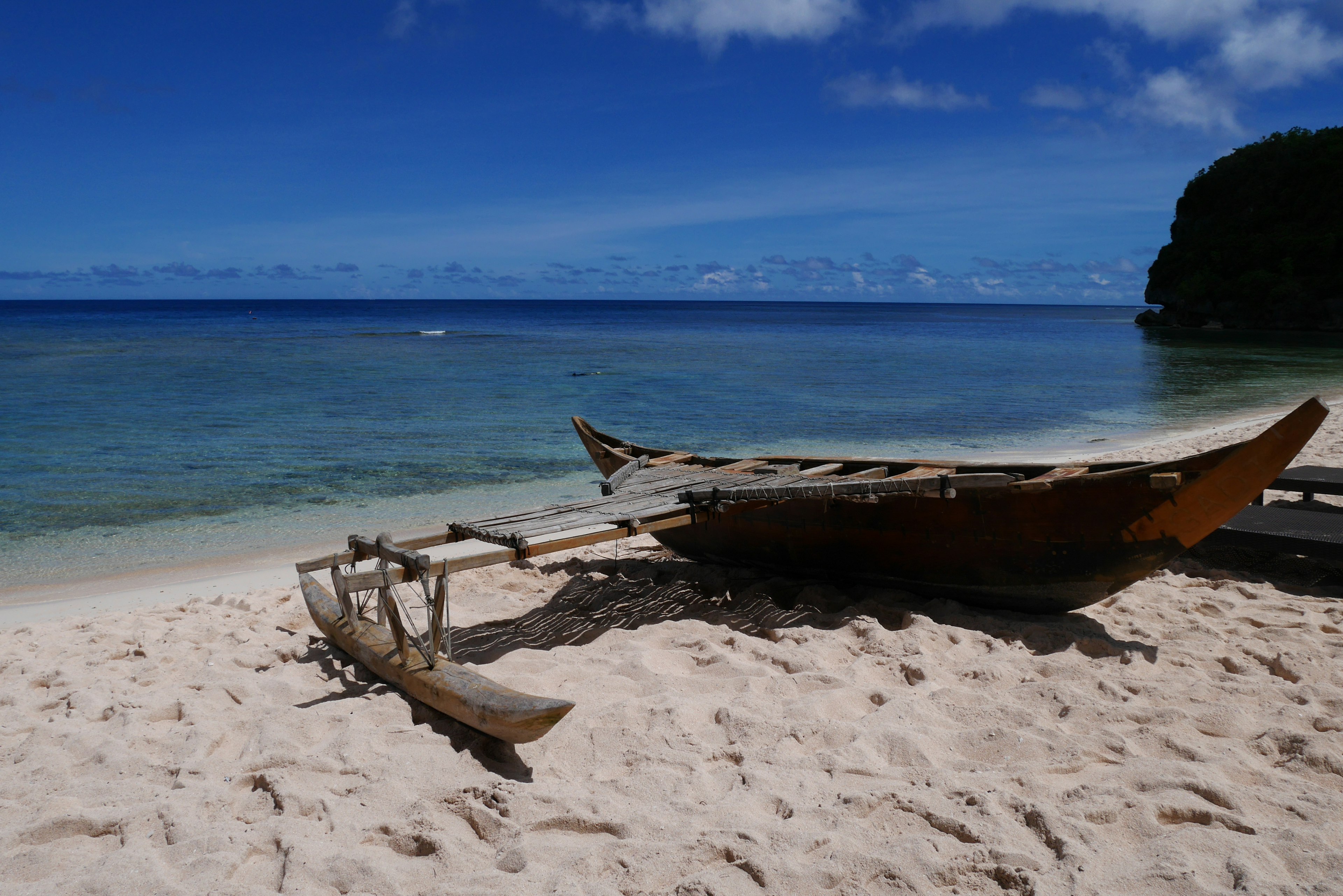 Barca di legno su una spiaggia di sabbia con mare e cielo blu chiaro