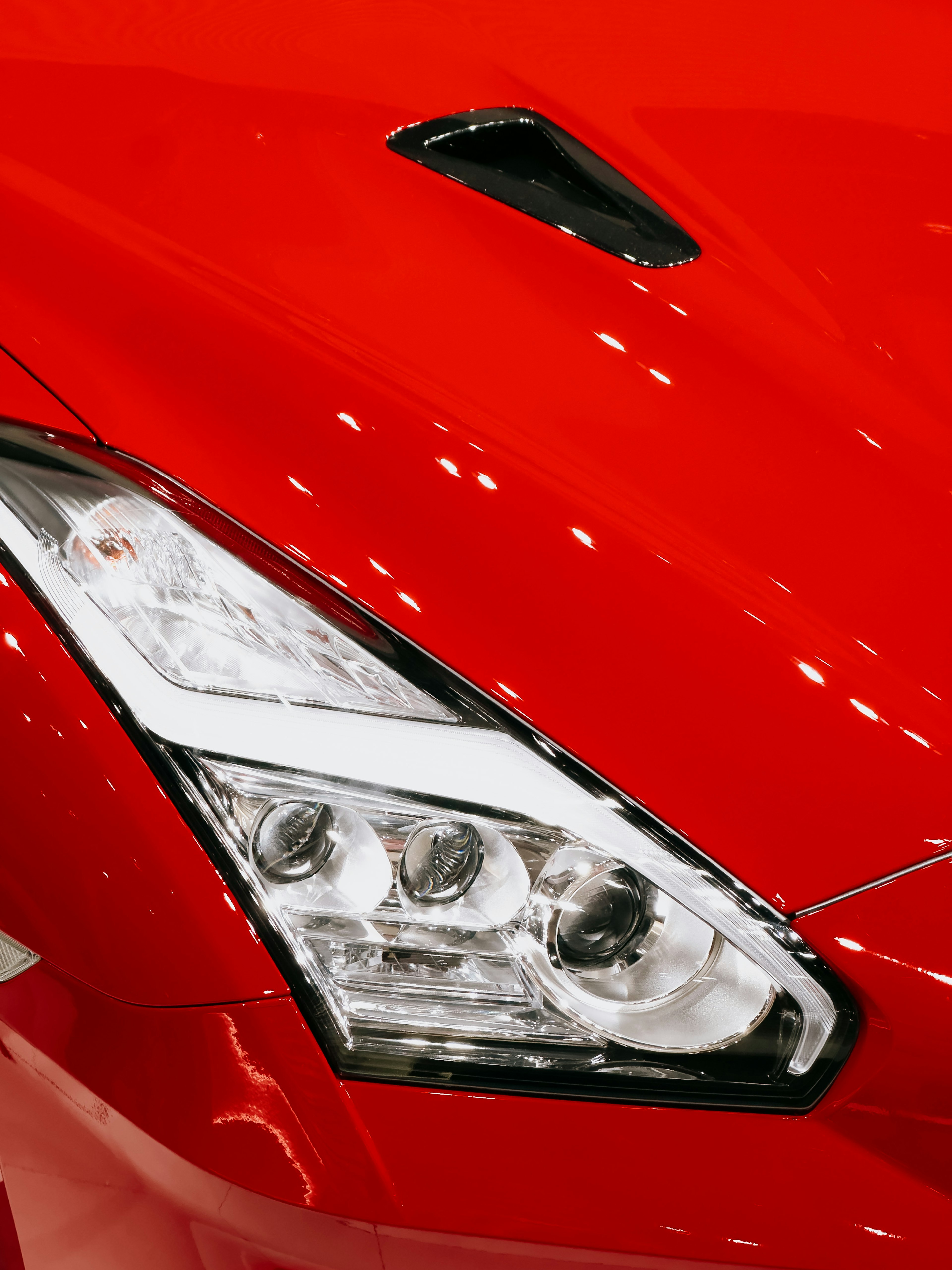 Close-up of a red sports car front featuring LED headlights and air intake