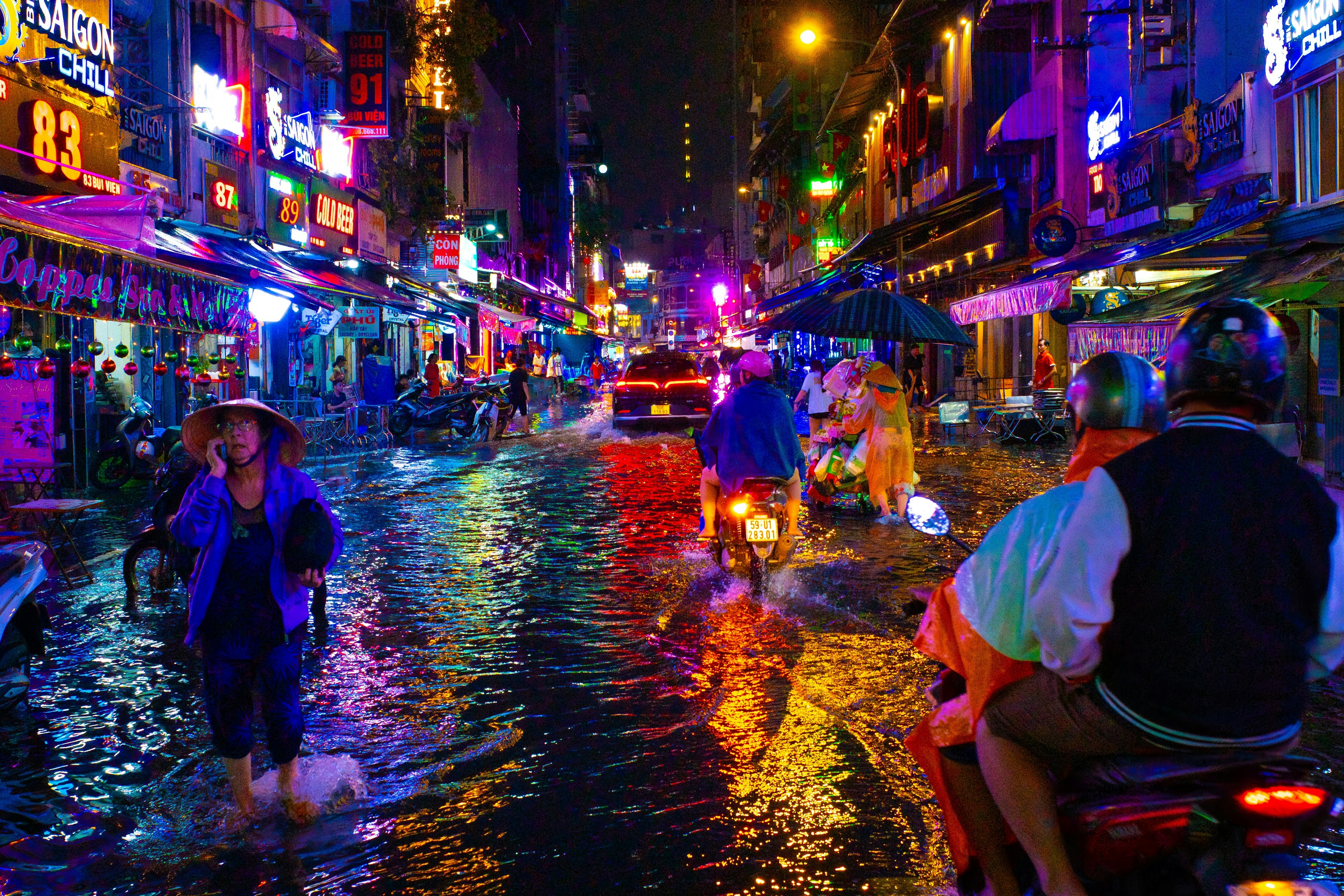 Flooded street at night with vibrant neon lights reflecting on water