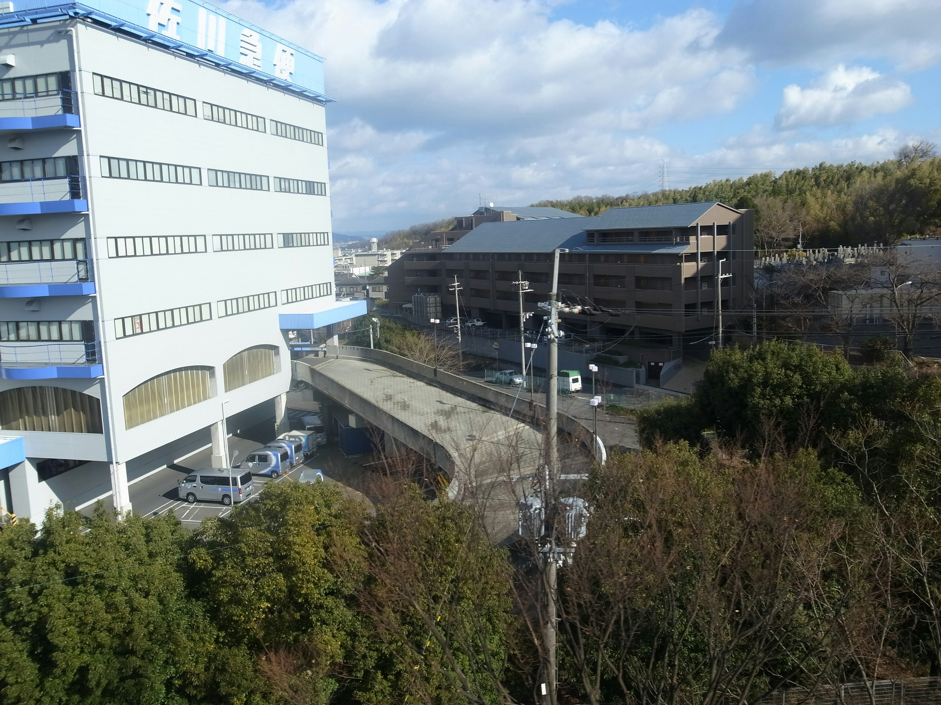 Vista de un edificio de techo azul rodeado de vegetación e infraestructura urbana